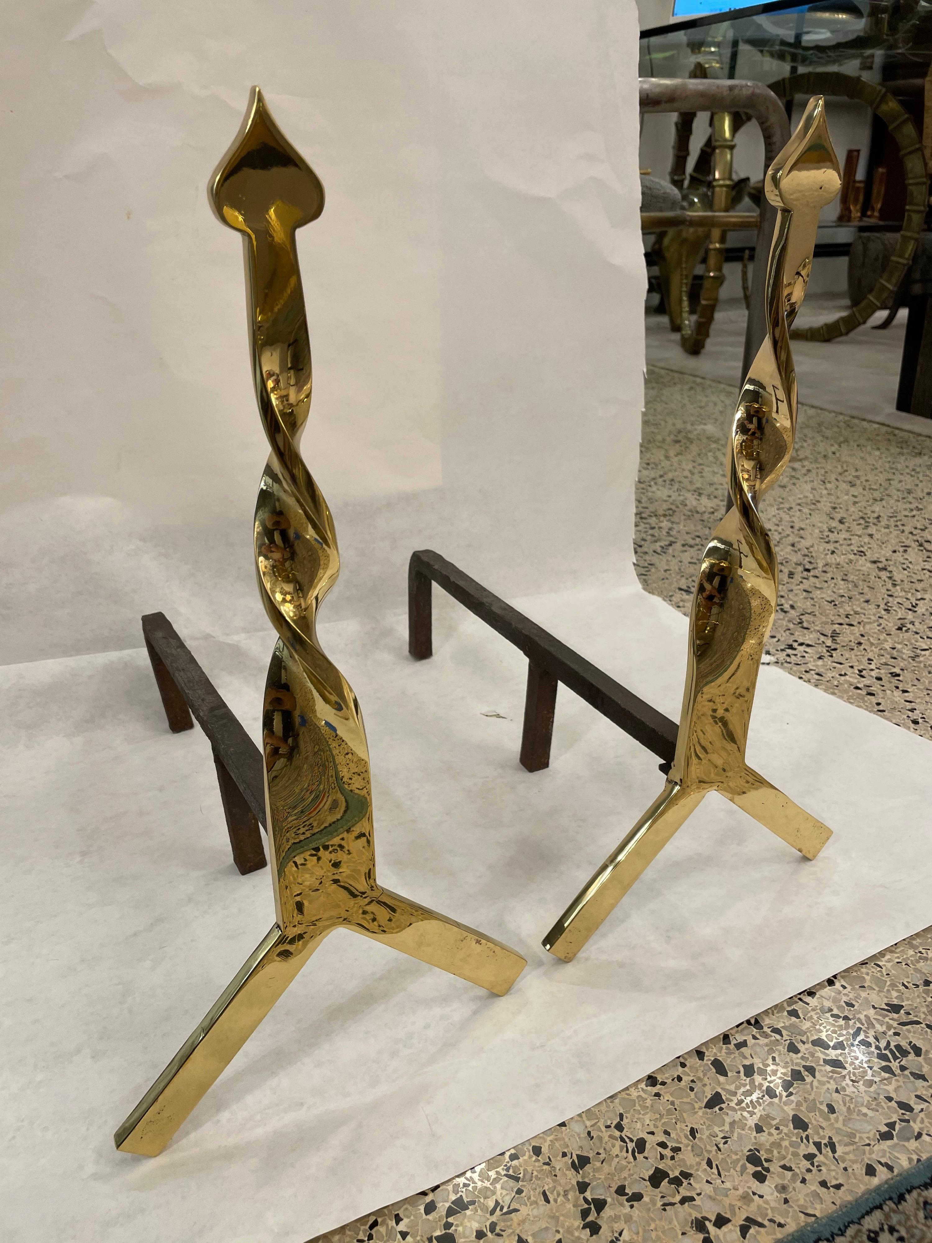 These simple and yet classic designed andirons in a polished brass with twisted neck and spade finial.