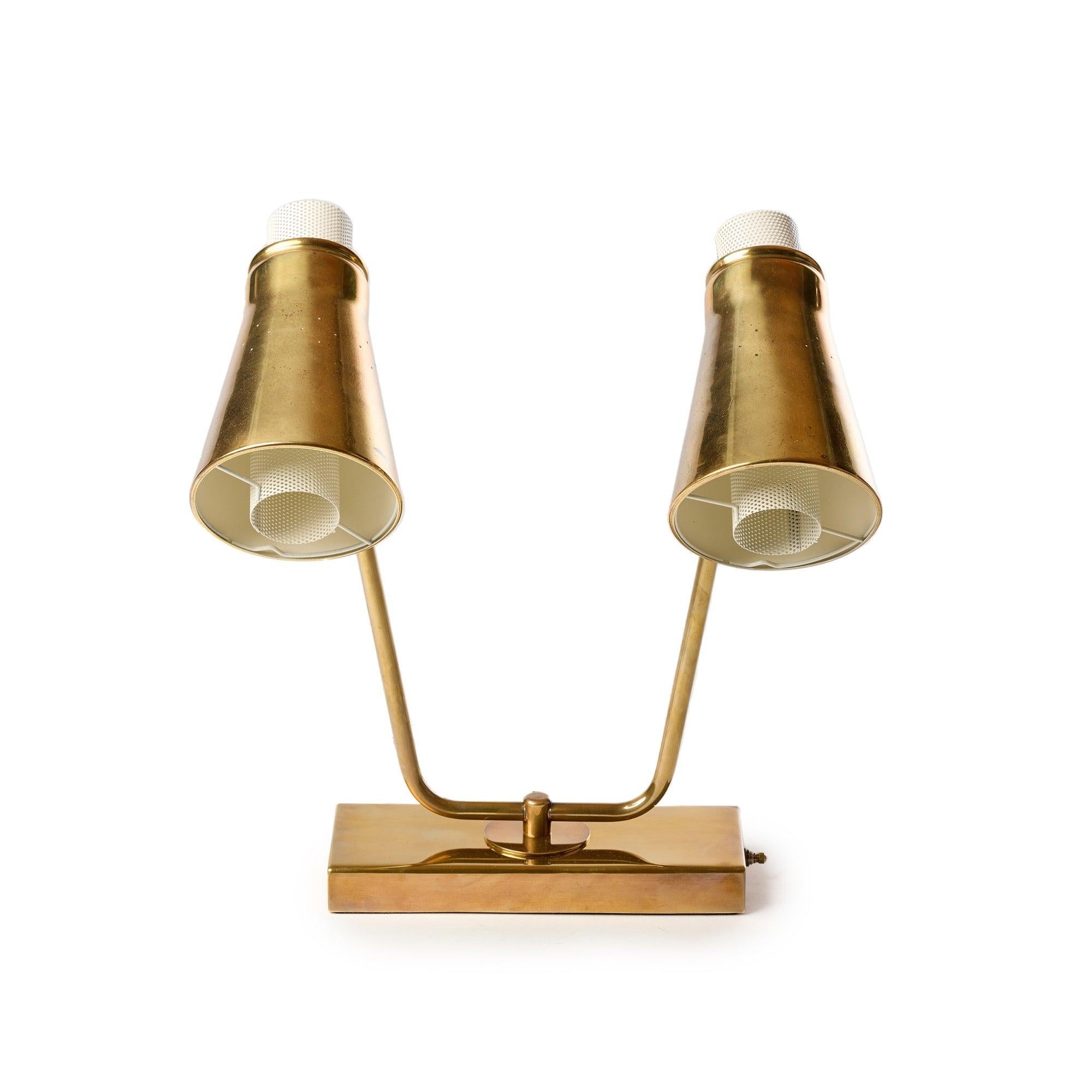 A distinctive and sculptural lacquered brass wall sconce having twin pin hole perforated swiveling conical shades with perforated cylindrical diffusers, projecting from a rectangular mounting plate. Can be wall mounted or used as a desk lamp.