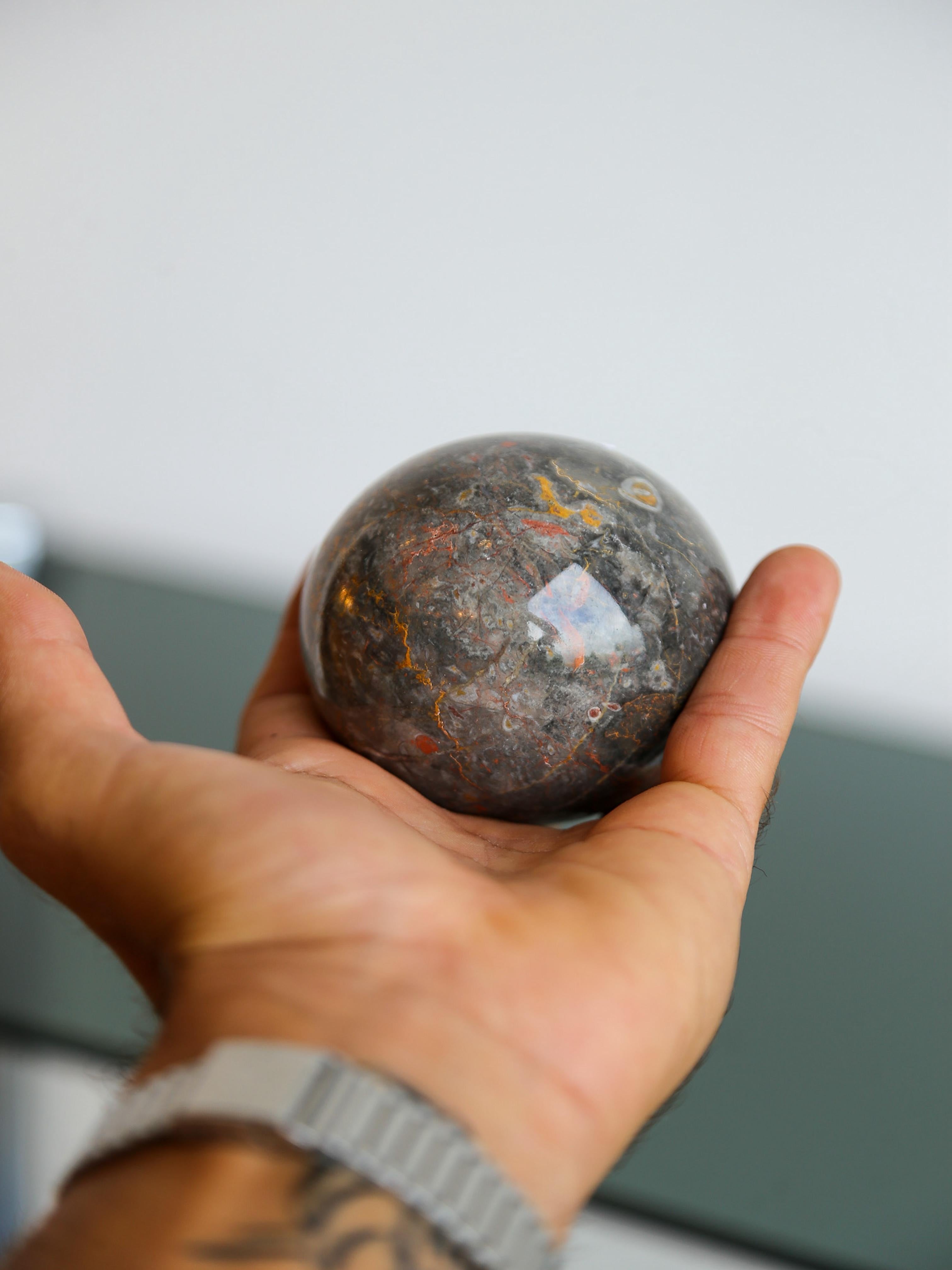Oggetto scultoreo dal fascino tattile e dall'intrigo visivo, questa sfera di marmo italiana risale agli anni '80 ed è meticolosamente scolpita nel marmo Breccia, apprezzato per le sue venature dinamiche e la colorazione terrosa e ricca di minerali.
