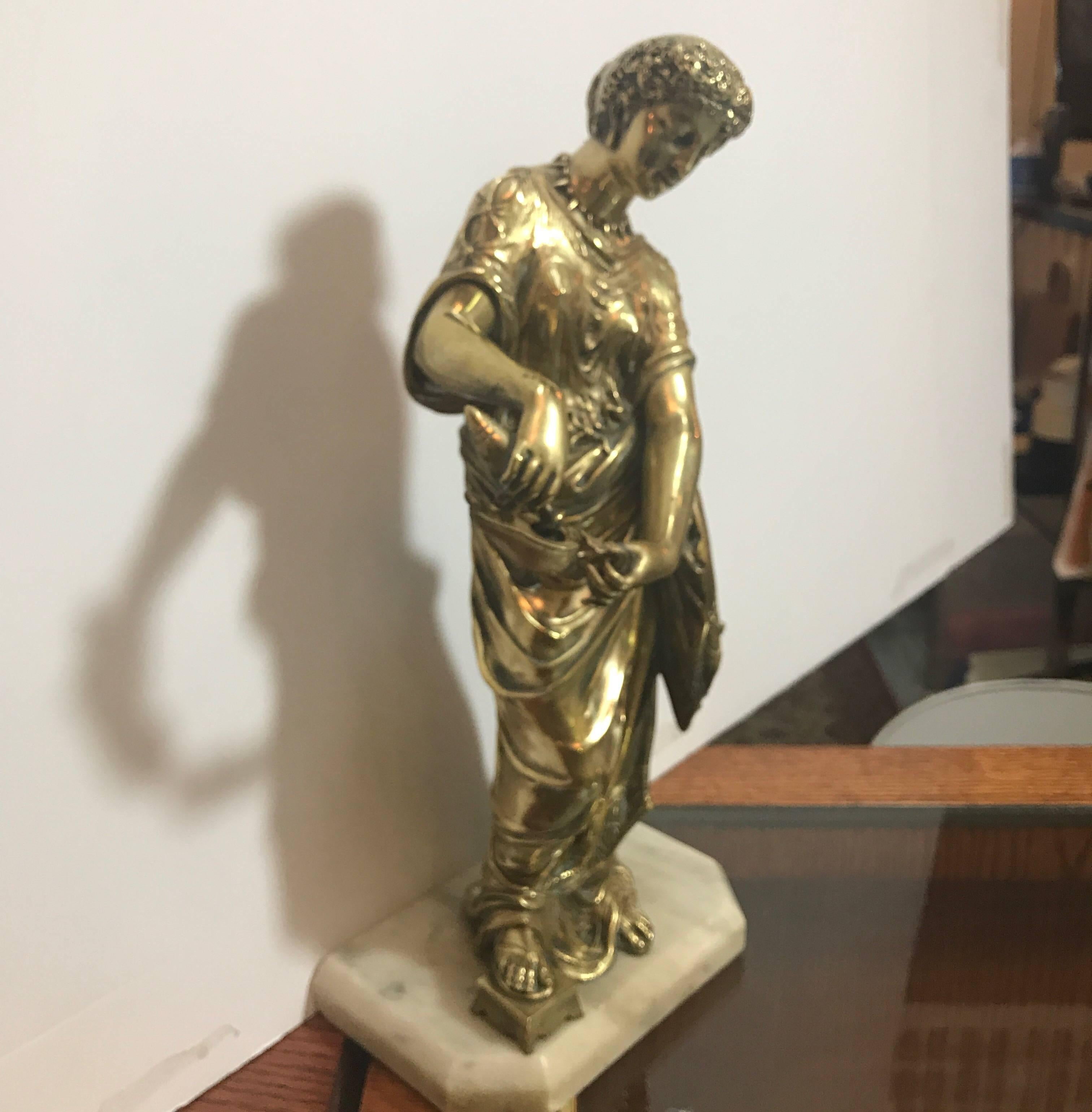 A beautifully cast bronze figure of a Greek maiden filling a lamp with oil. The polished bronze figure on white marble base in classic ancient Grecian dress.