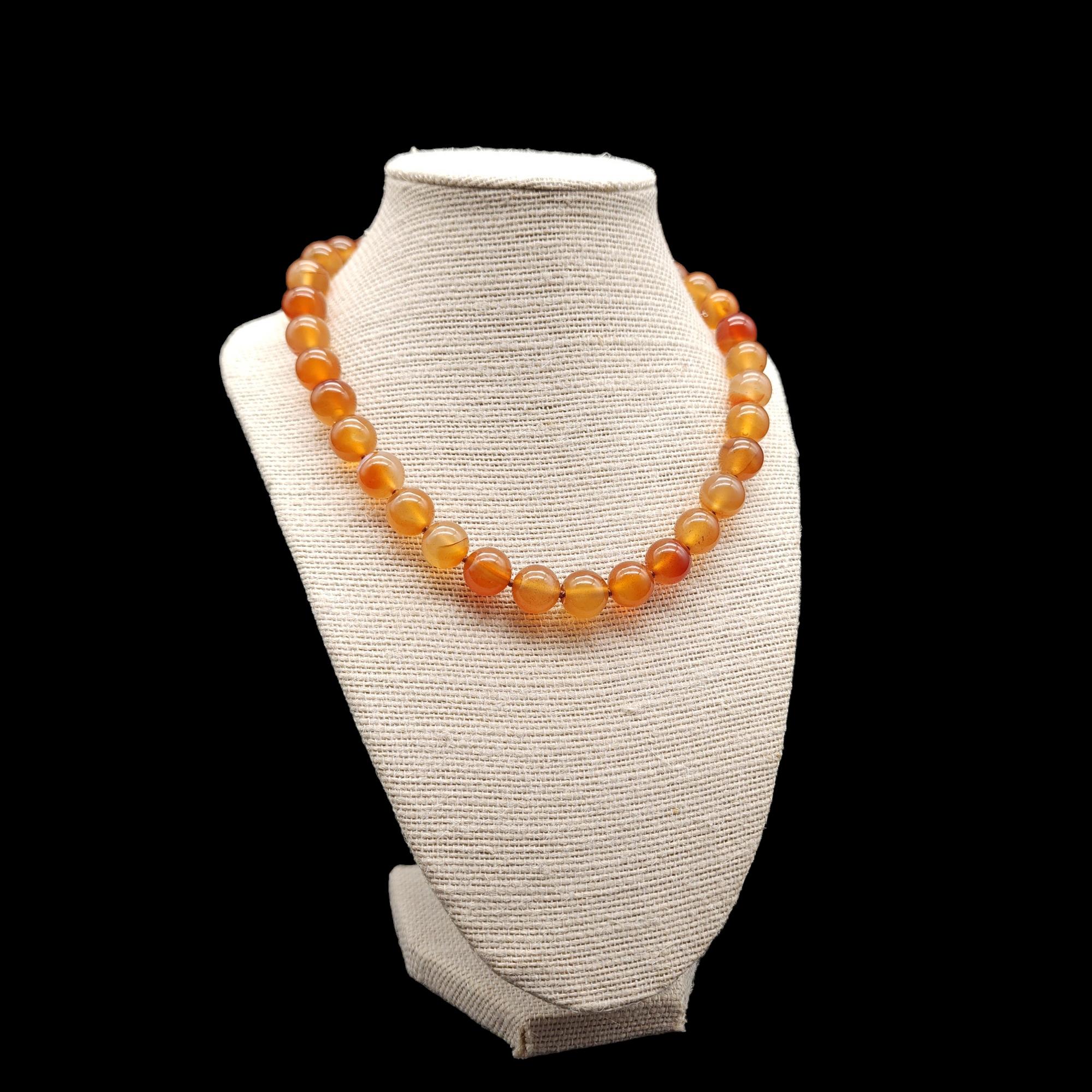 This necklace is a vintage piece that features polished carnelian beads and a sterling silver clasp. It’s designed to be worn as a collar necklace and is in excellent condition. The carnelian beads are polished to a high shine, and the sterling