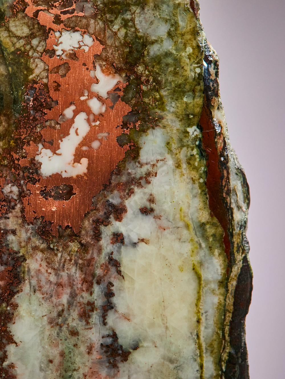 This striking polished quartz slice from the USA features rich native
copper inclusions that streak through the stone like molten metal, framed
by natural green tones that evoke a painterly, abstract landscape. The
mirror-like surface enhances the