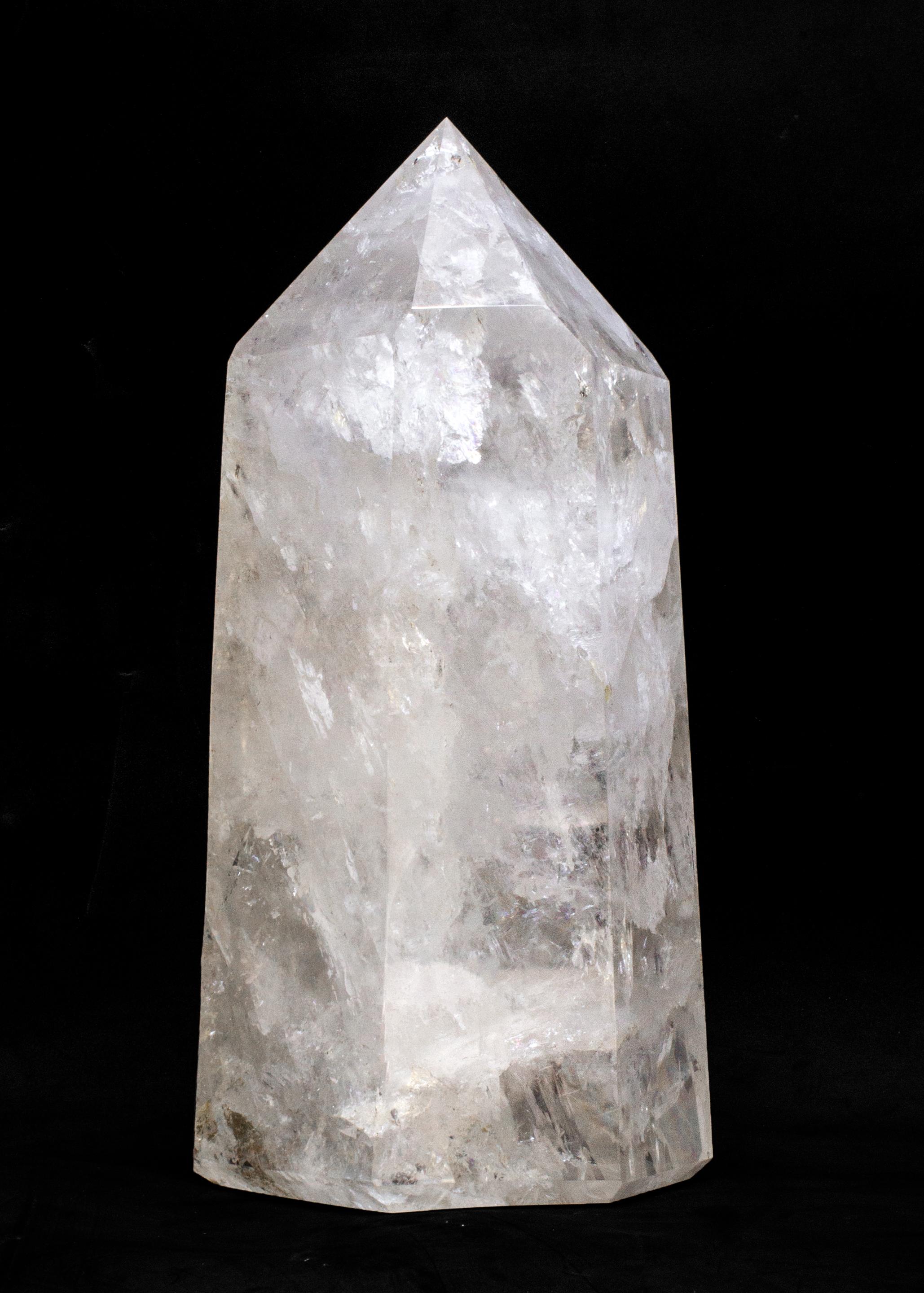 Obelisk aus poliertem Kristallquarz.

Die polierte Quarzkristallspitze stammt aus Brasilien. Er wird von Hand geschliffen und facettiert, um die Form eines sechsseitigen Obelisken zu erhalten, und er enthält natürliche Verschlüsse. Es ist sehr
