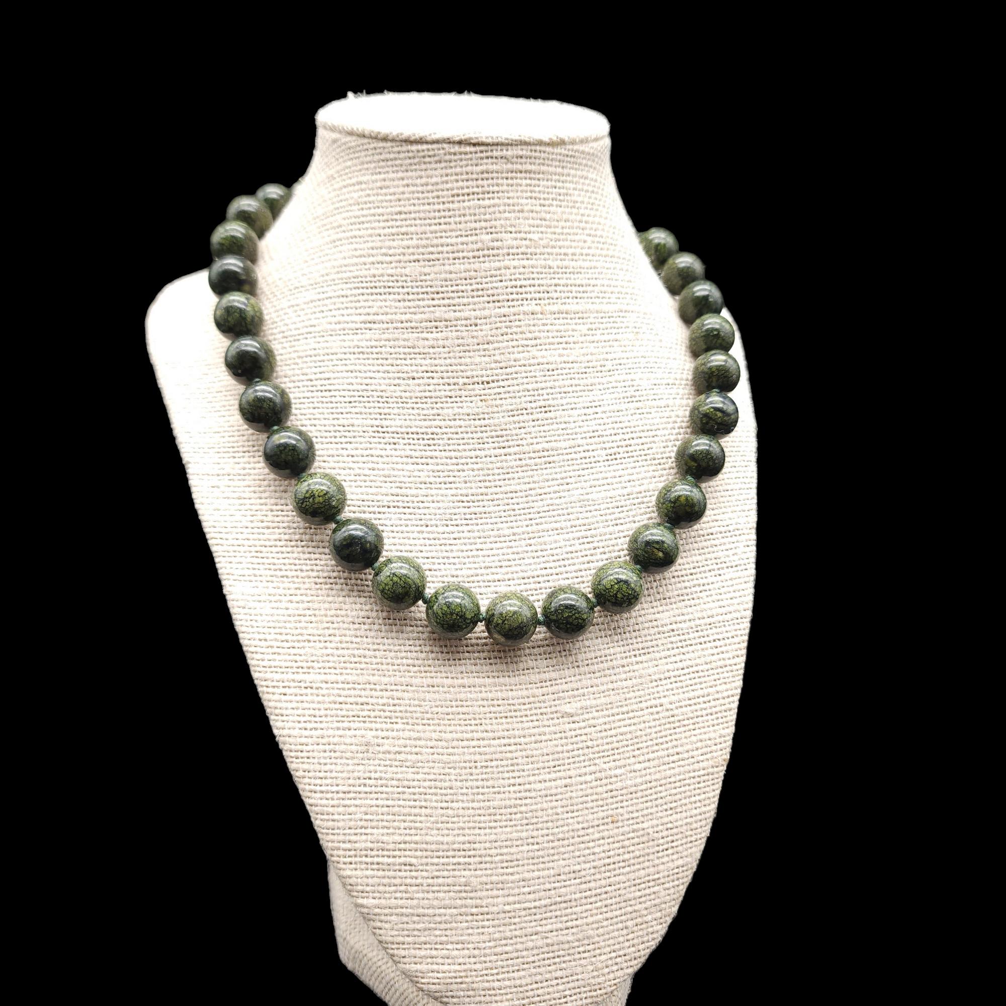 This Polished Jade Bead Necklace is a stunning piece of vintage jewelry that is sure to turn heads! The necklace features dark green jade beads that have been polished to a high shine, giving them a beautiful luster. The beads are strung together on
