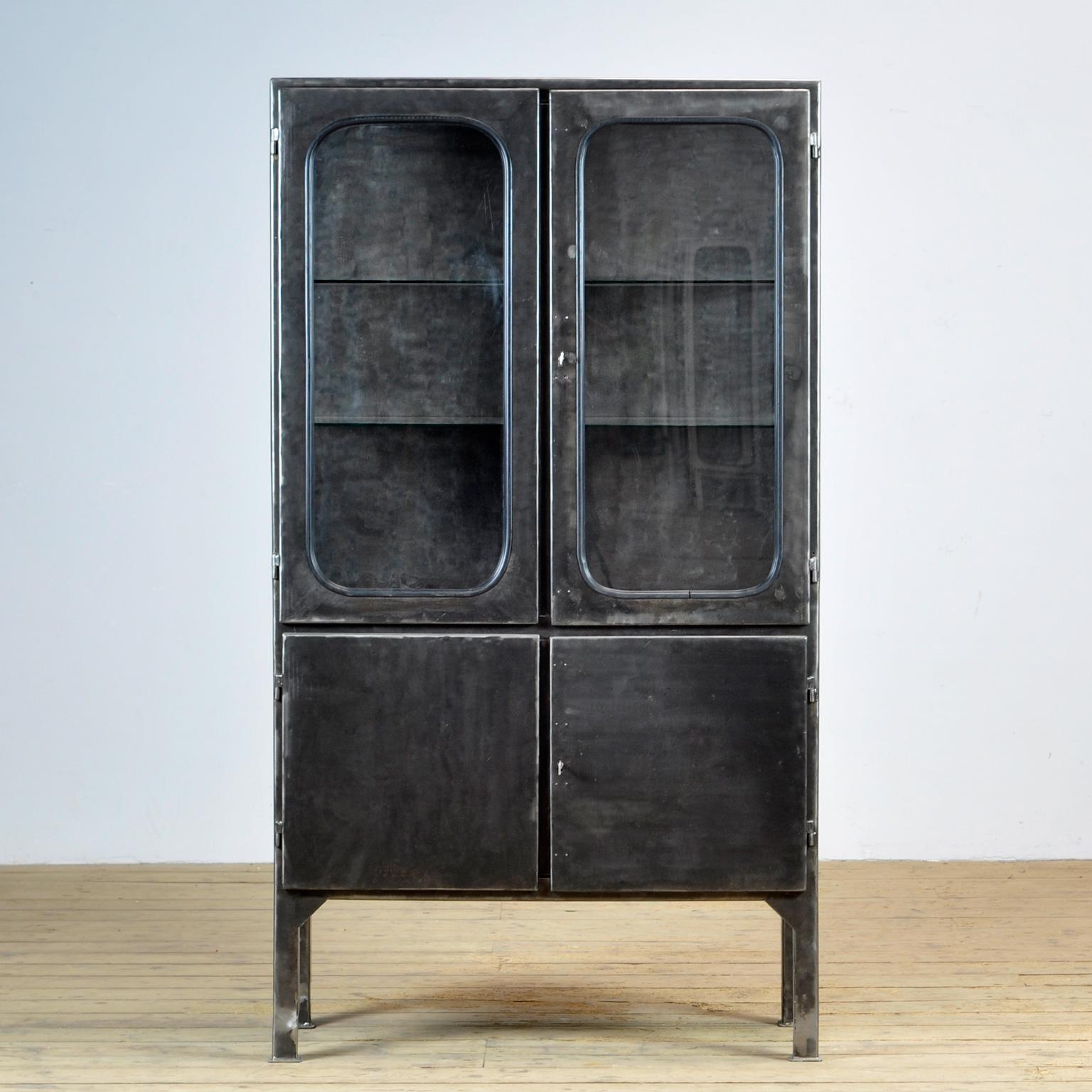 Made of steel and glass that is clamped in the steel by a rubber strip. The cabinet is from the 1970s and was produced in Hungary. The cabinet has been stripped to the metal and finished with a transparent lacquer. The cabinet comes with 2 glass