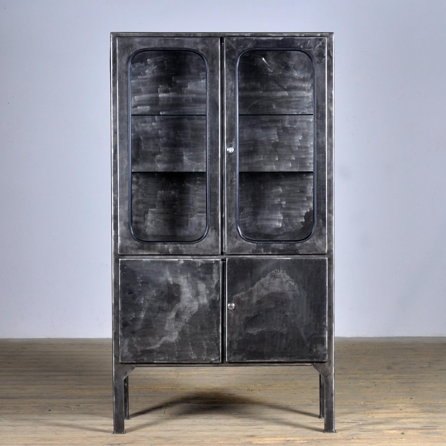 Made of steel and glass that is clamped in the steel by a rubber strip. The cabinet is from the 1970s and was produced in Hungary. The cabinet has been stripped to the metal and finished with a transparent lacquer. The cabinet comes with 2 glass