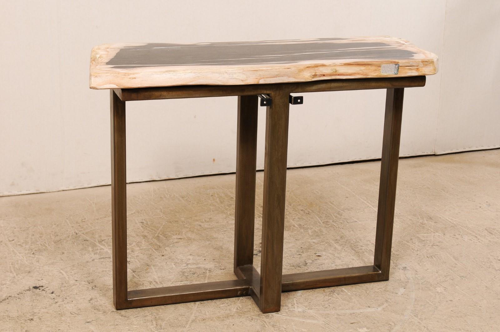 Une table console au design moderne avec un plateau en bois pétrifié. Cette table console personnalisée a été façonnée à partir d'une seule dalle épaisse de bois pétrifié poli et lisse, d'une longueur d'environ 1,5 mètre. Ce fabuleux plateau en bois