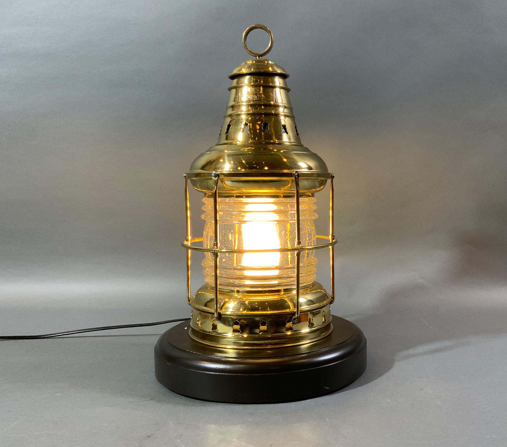Polished ships lantern by the Perkins Marine Lamp Corporation, also known as Perko. The lantern is fitted with protective brass bars, a Fresnel glass lens, vented top, and hoisting ring. It has been recently rewired for home use. Mounted to a thick