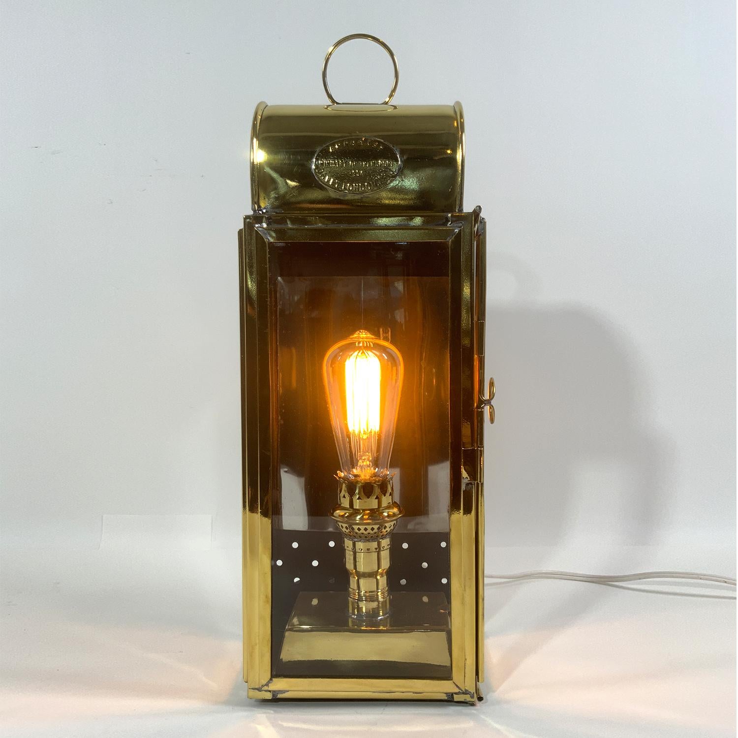 Polished and lacquered Ministry of Transport approved cabin lantern by Davey of London. With makers badge dated 1954. The oil burner has been replaced with an AC socket. Hinged door. Vented top. Carry handle.