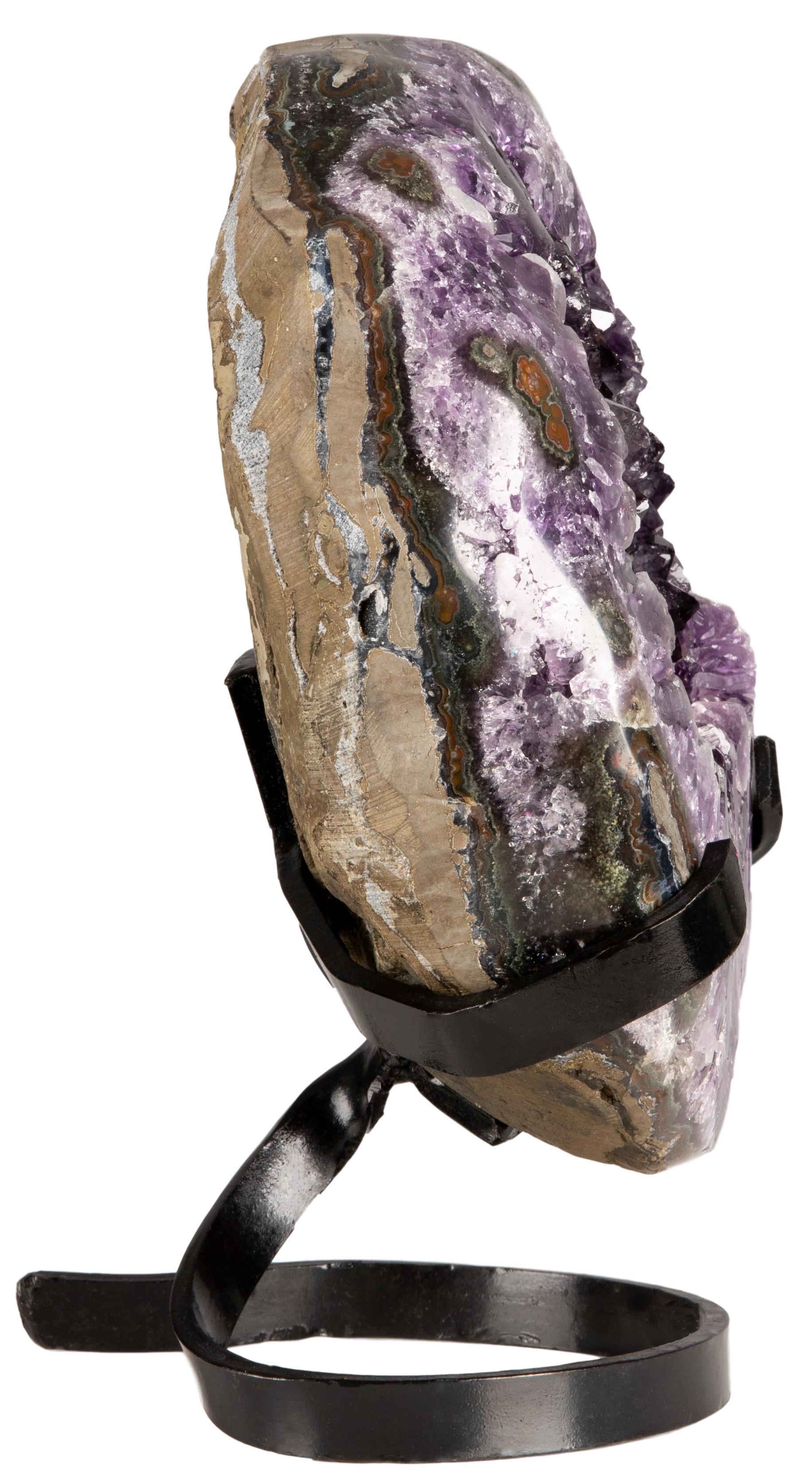 An exquisite cut and polished partial amethyst geode with a circular shape. The front of the piece presents beautiful, vibrant, deep purple color amethyst with high peaked crystals. A polished stalactite can be observed in the lower portion,