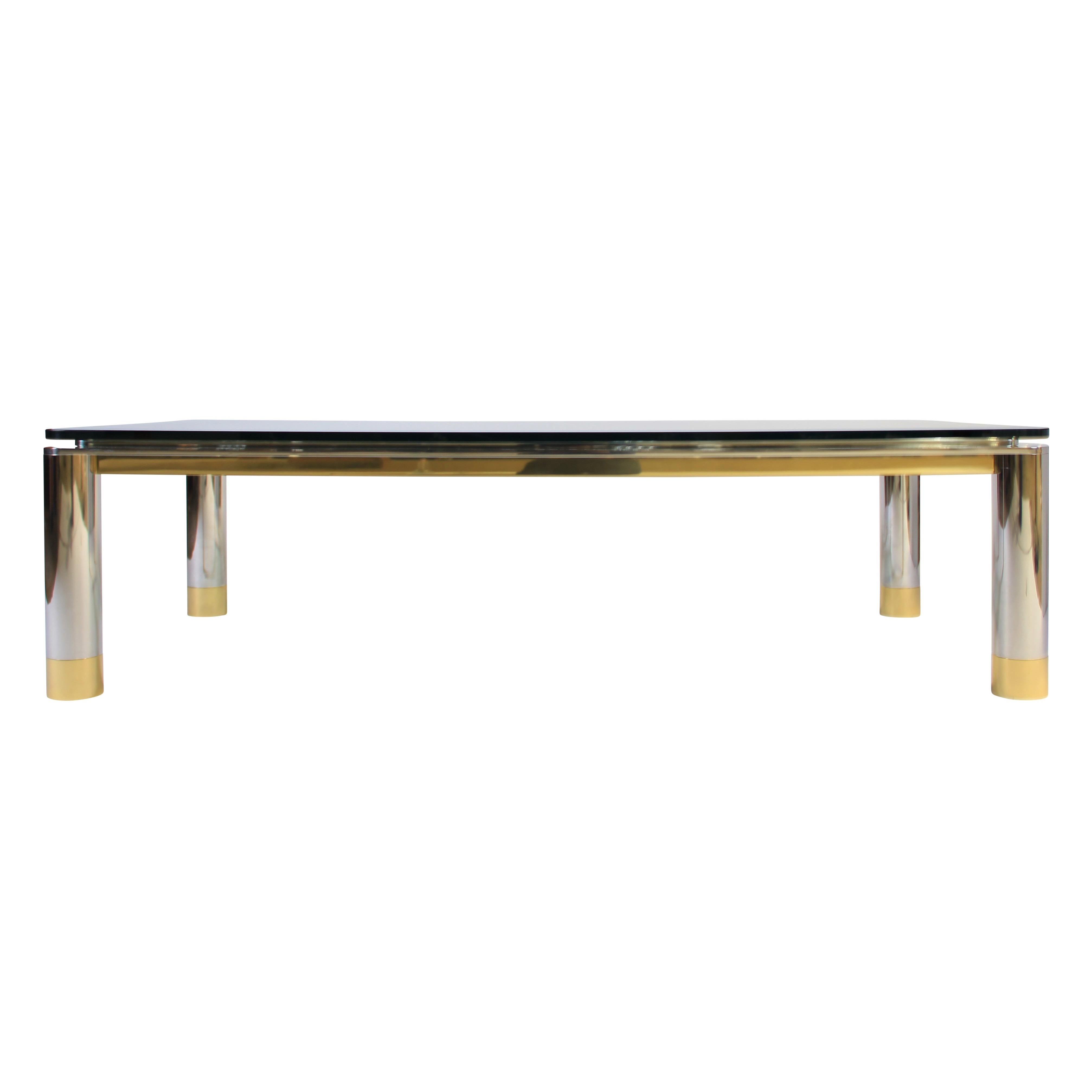 Stunning and beautifully made rectangular coffee table features a heavy polished stainless steel frame and cylindrical legs with a polished-brass skirt and feet. We can't emphasize enough how substantial this piece is, and please note that both the
