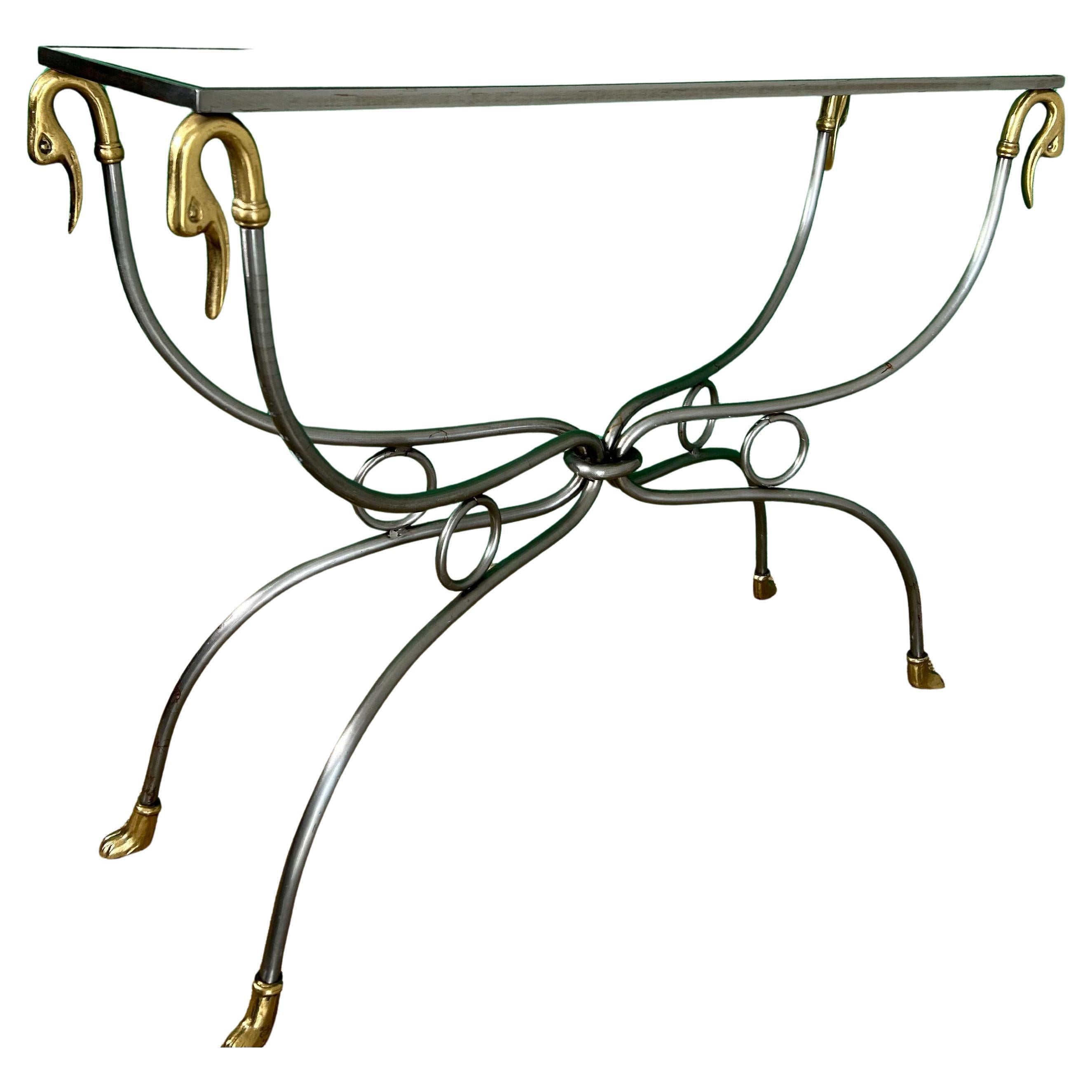 Elegantly shaped and skillfully crafted, this console table is adorned with gilded brass accents on a polished steel frame and base.

While there is no maker's mark, the craftsmanship and style would suggest that this table hails from the prominent