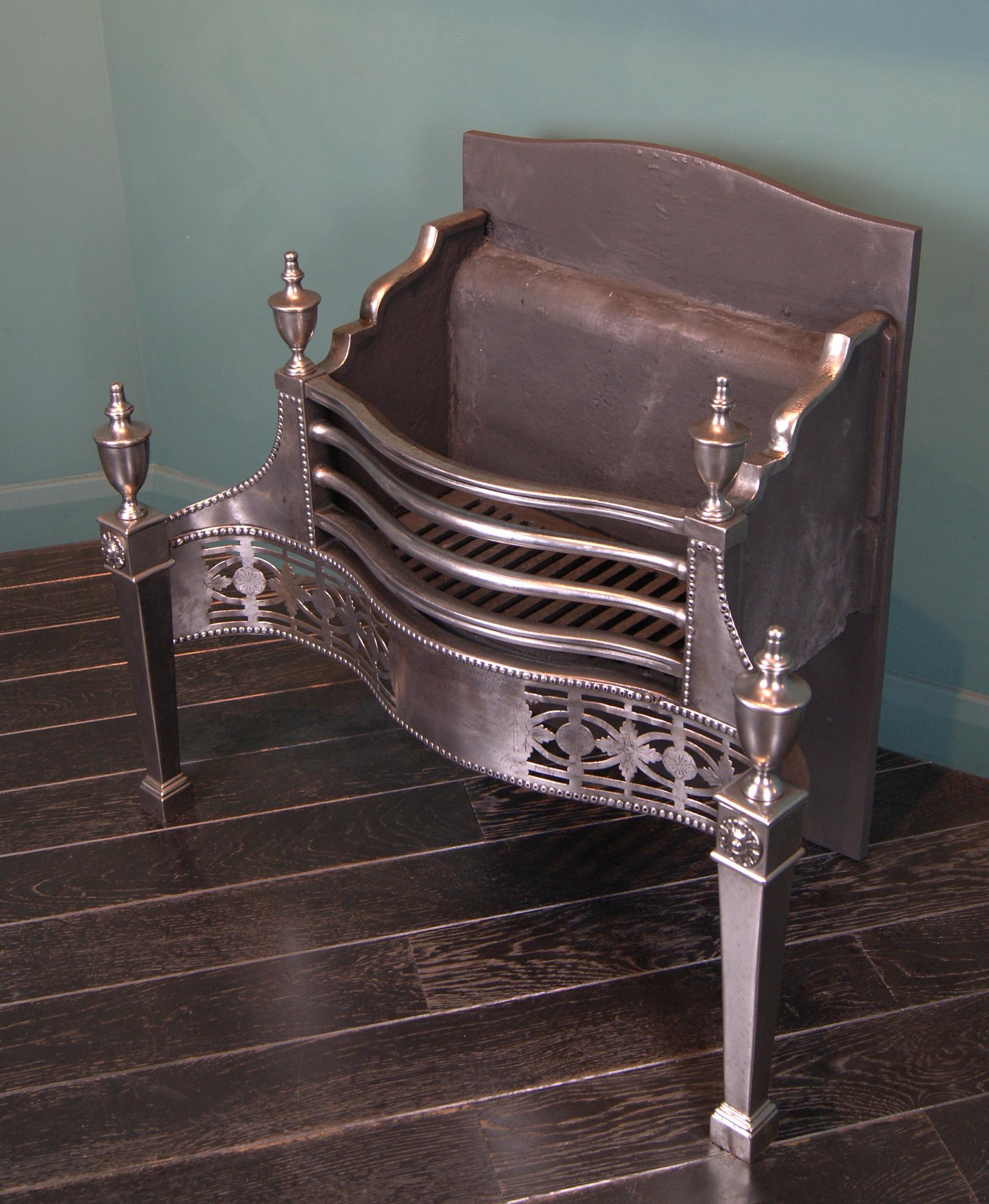 A fine polished steel Georgian revival dog grate of serpentine form. The shaped fire bars, pierced engraved fret supported on tapered legs with urn finials uppermost. Fire back with brick on roller wheels. Restored.

Circa 1890.