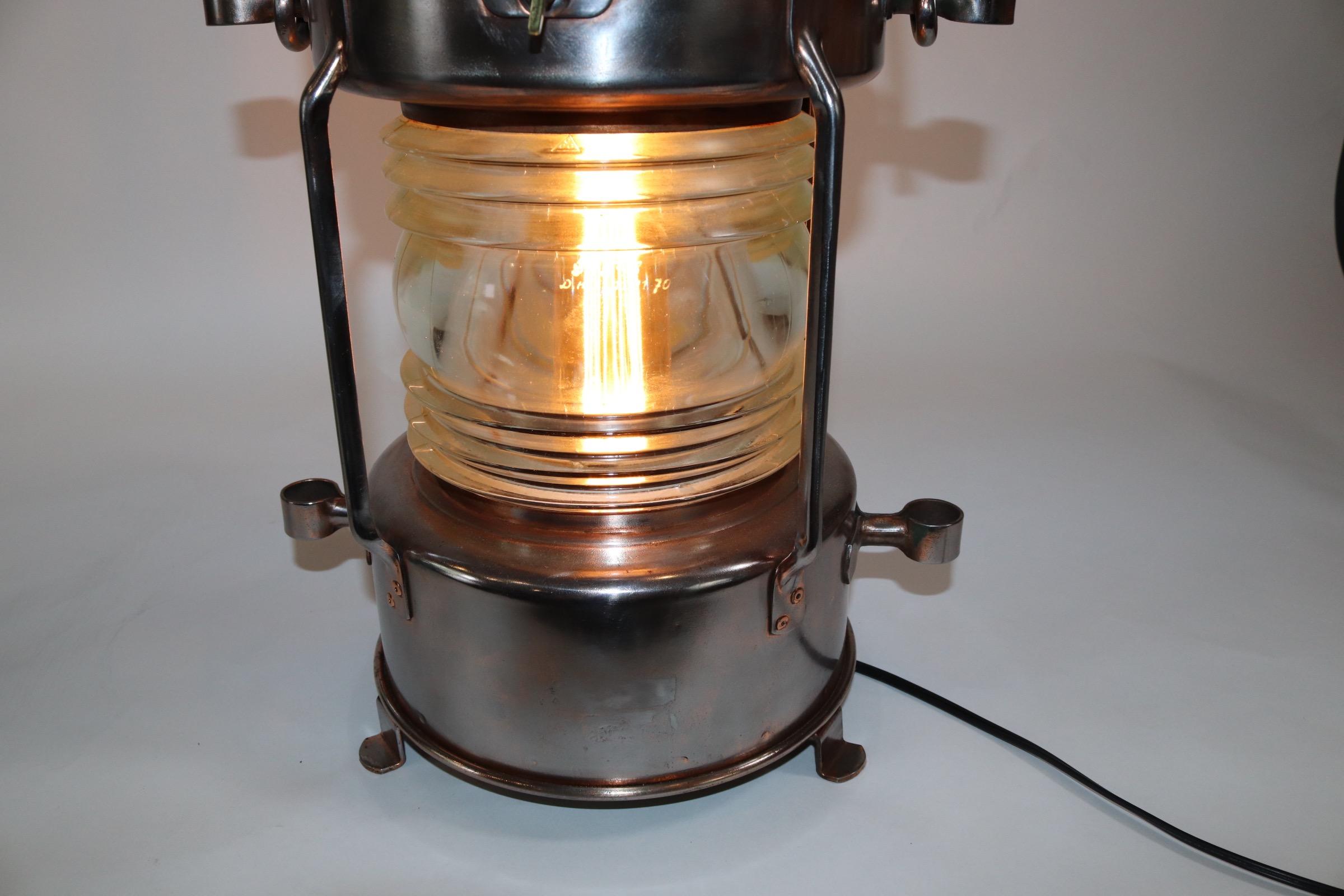 Polished steel ships anchor lantern with copper cap, carry handle, glass Fresnel lens, and the lantern is electrified for home use. Weight is 13 pounds.