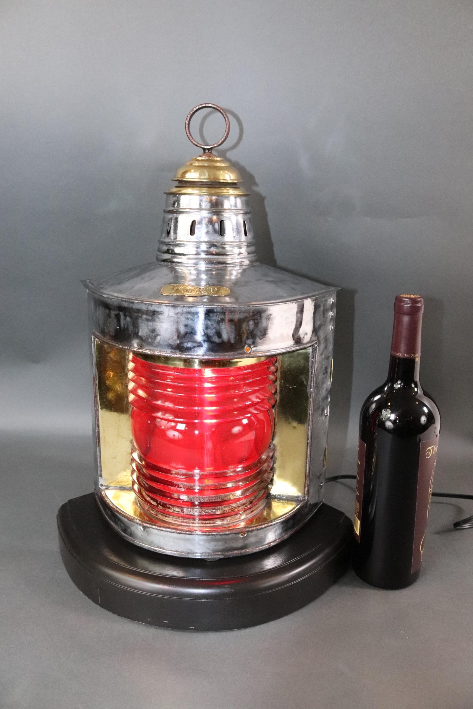 Polished steel and brass ships lantern with red Fresnel glass lens. Mounted to a custom made thick mahogany base with dark finish. With makers badge from J.Barre & Co. manufacturers 25 Fulton & 204 Water St N.Y. Hinged rear door, interior is fitted