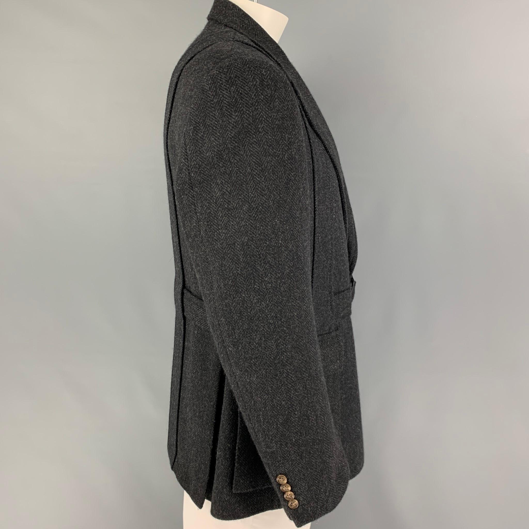 POLO by RALPH LAUREN coat comes in a dark gray herringbone virgin wool with a full liner featuring a belted style, notch lapel, flap pockets, and a buttoned closure. Made in Italy.

Very Good Pre-Owned Condition.
Marked: 46