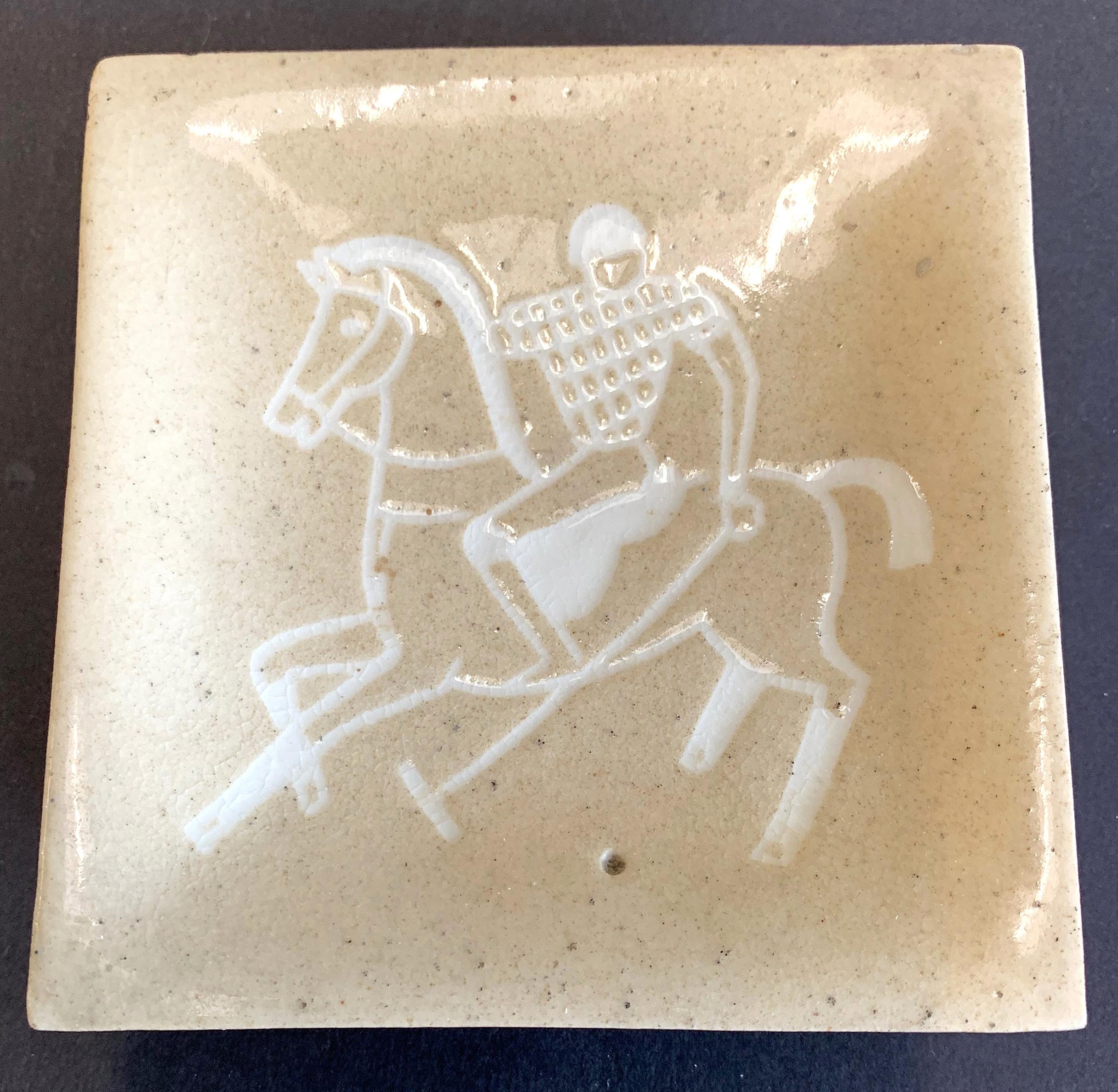 Beautifully glazed in shades of white and sand, this rare footed dish depicts a polo player reaching out to strike the ball. The primary glaze has a beautiful mottled appearance, and the artist -- Waylande Gregory -- very cleverly represented the