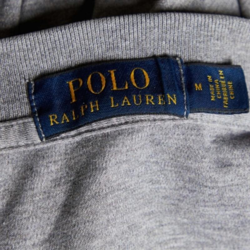Le magliette polo di Polo Ralph Lauren sono sempre state un classico per gli uomini. Questa versione è realizzata in cotone grigio e rifinita con l'iconico logo e l'abbottonatura. Completa il tuo look casual con un paio di pantaloncini e scarpe da