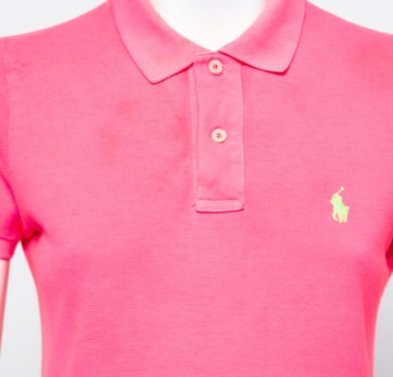 Realizzata in cotone morbido e traspirante, questa T-shirt di Polo Ralph Lauren è caratterizzata da chiusura frontale con bottoni, colletto semplice e maniche corte. La tonalità rosa neon conferisce un tocco di dolcezza al pezzo, rendendolo ideale