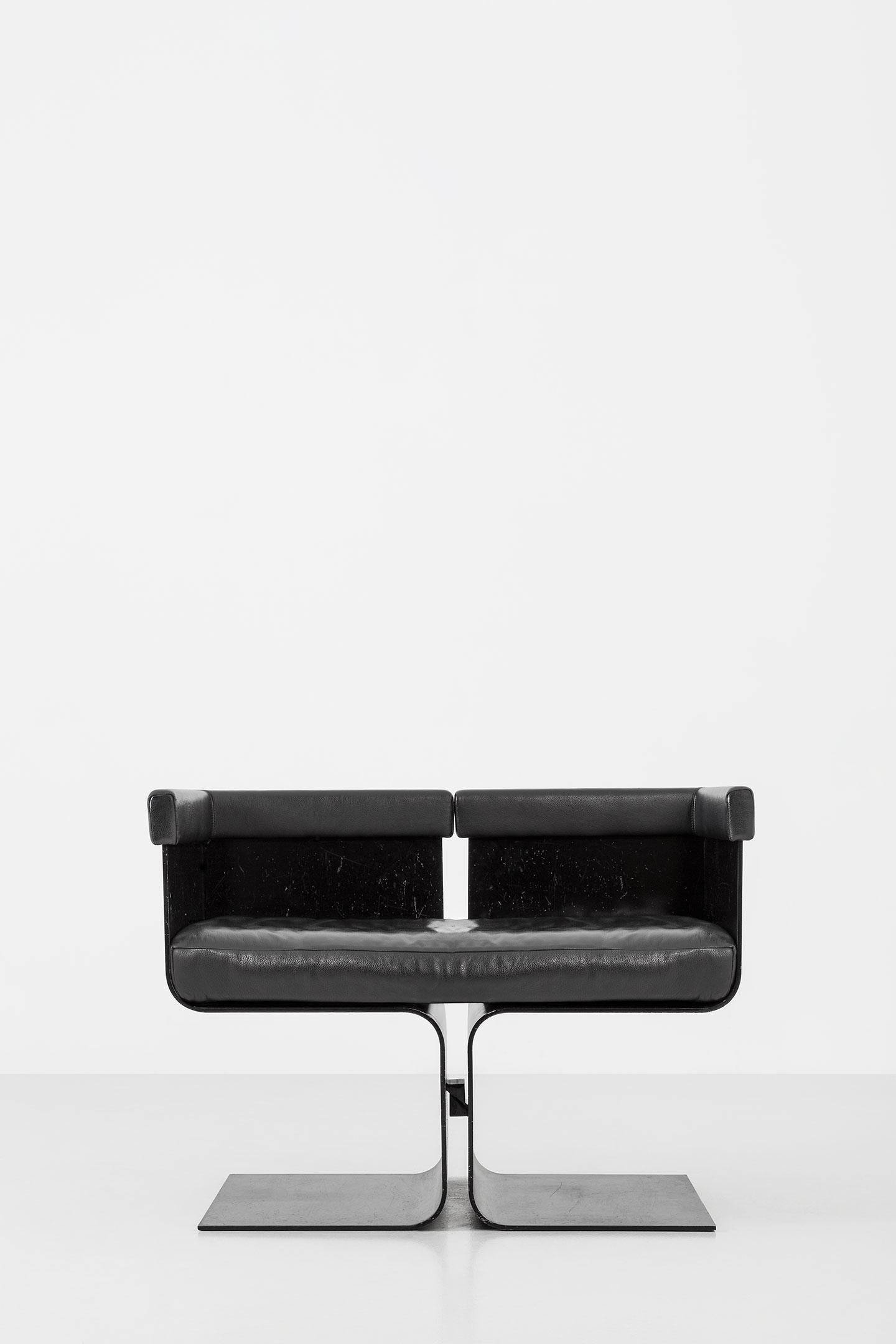 Armchair composed of two C-shaped black painted metal elements.
Cushion padded with polyurethane foam and upholstered in black leather.
Progetto Non Finito collection.