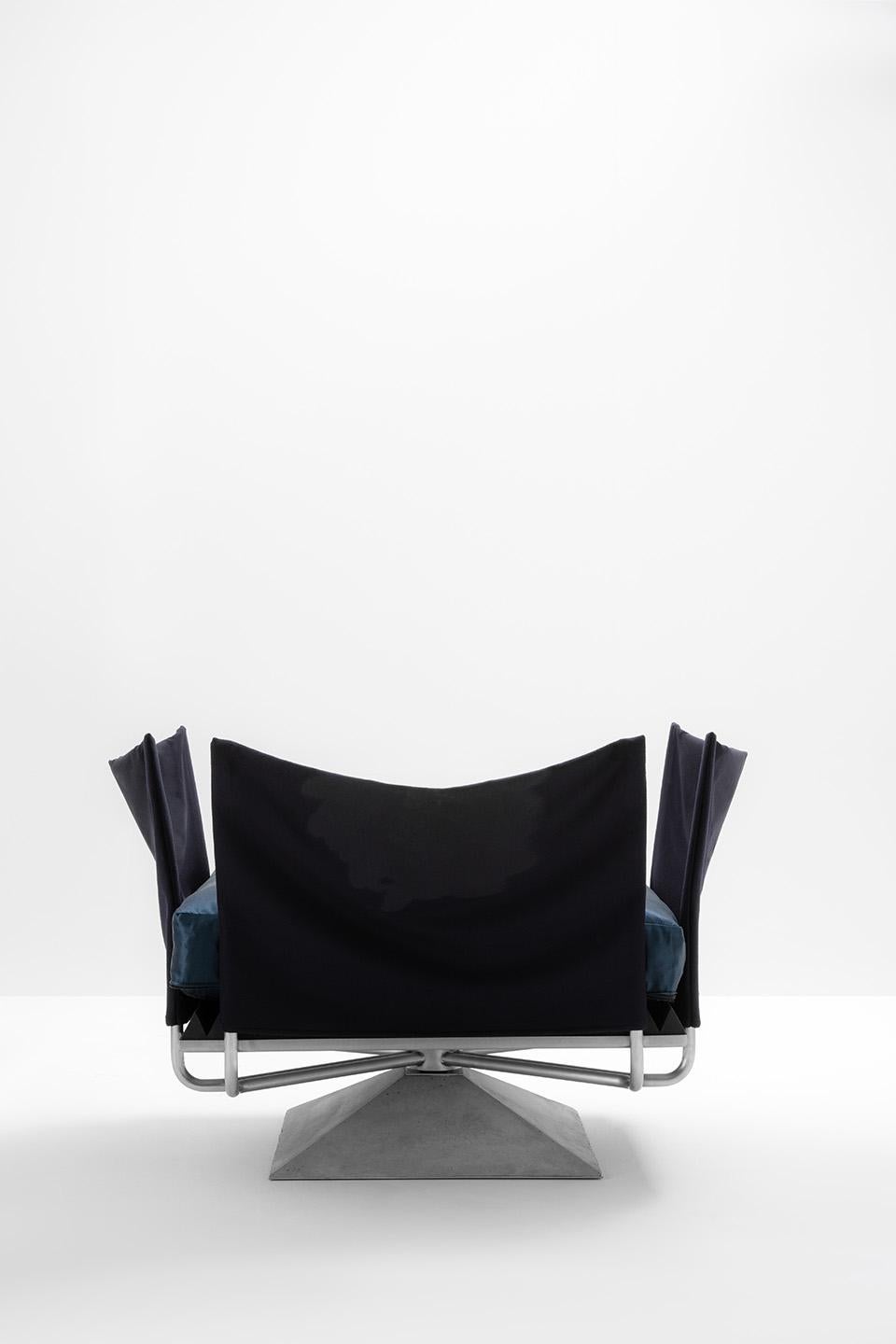 Armchair with a cement base. Structure in brushed steel with seat in triangular foam and cushion upholstered in Satin Dark Blue fabric. Backrest and armrests in decorated Wool Blue fabric with decoration.