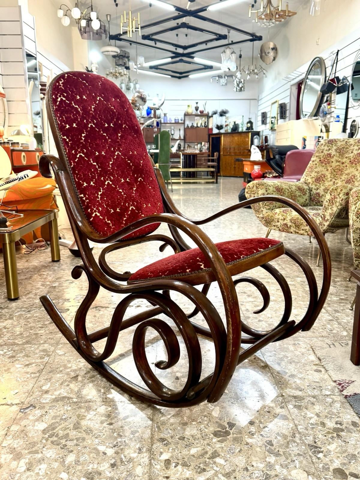 Elegante poltrona a dondolo Thonet, risalente al periodo mid-century, iconica per la sua silhouette sinuosa e il lavoro raffinato.

La struttura è realizzata in legno curvato a vapore caratterizzata da linee fluide e motivi a volute che conferiscono