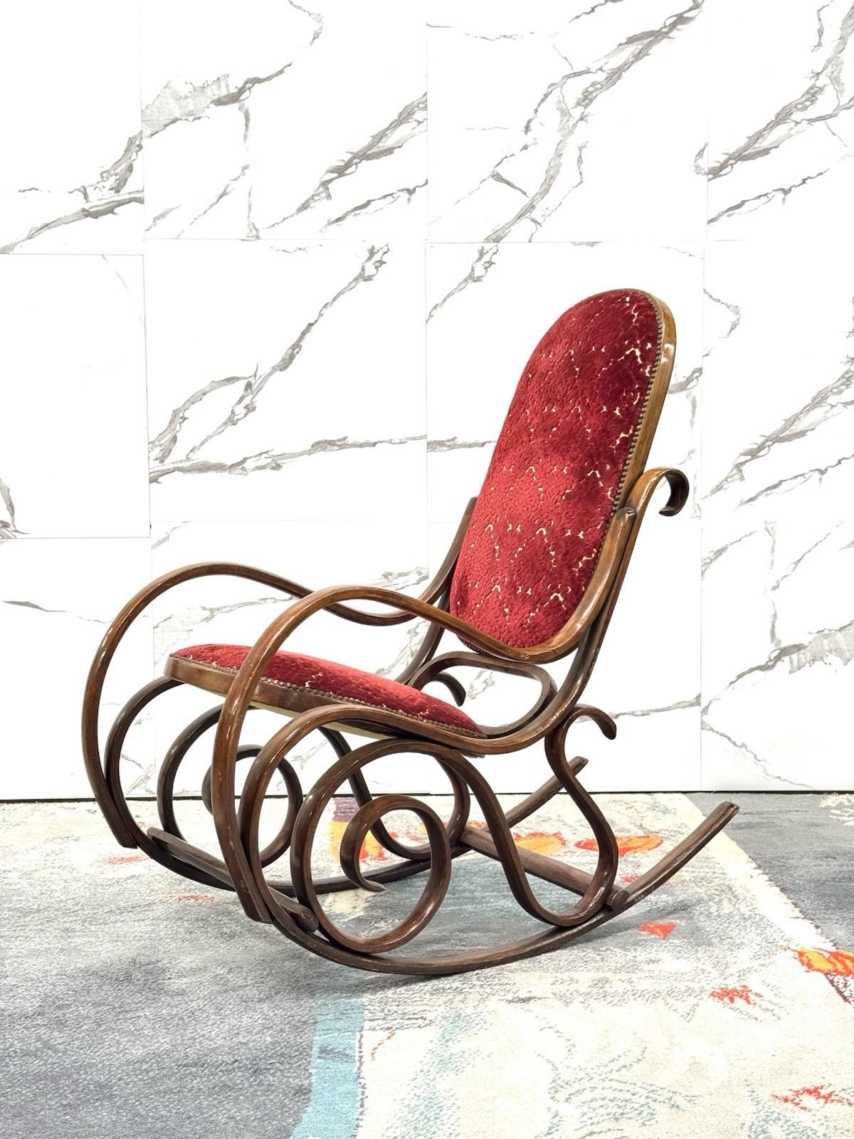 Elegante poltrona a dondolo Thonet, risalente al periodo mid-century, iconica per la sua silhouette sinuosa e il lavoro raffinato.

La struttura è realizzata in legno curvato a vapore caratterizzata da linee fluide e motivi a volute che conferiscono