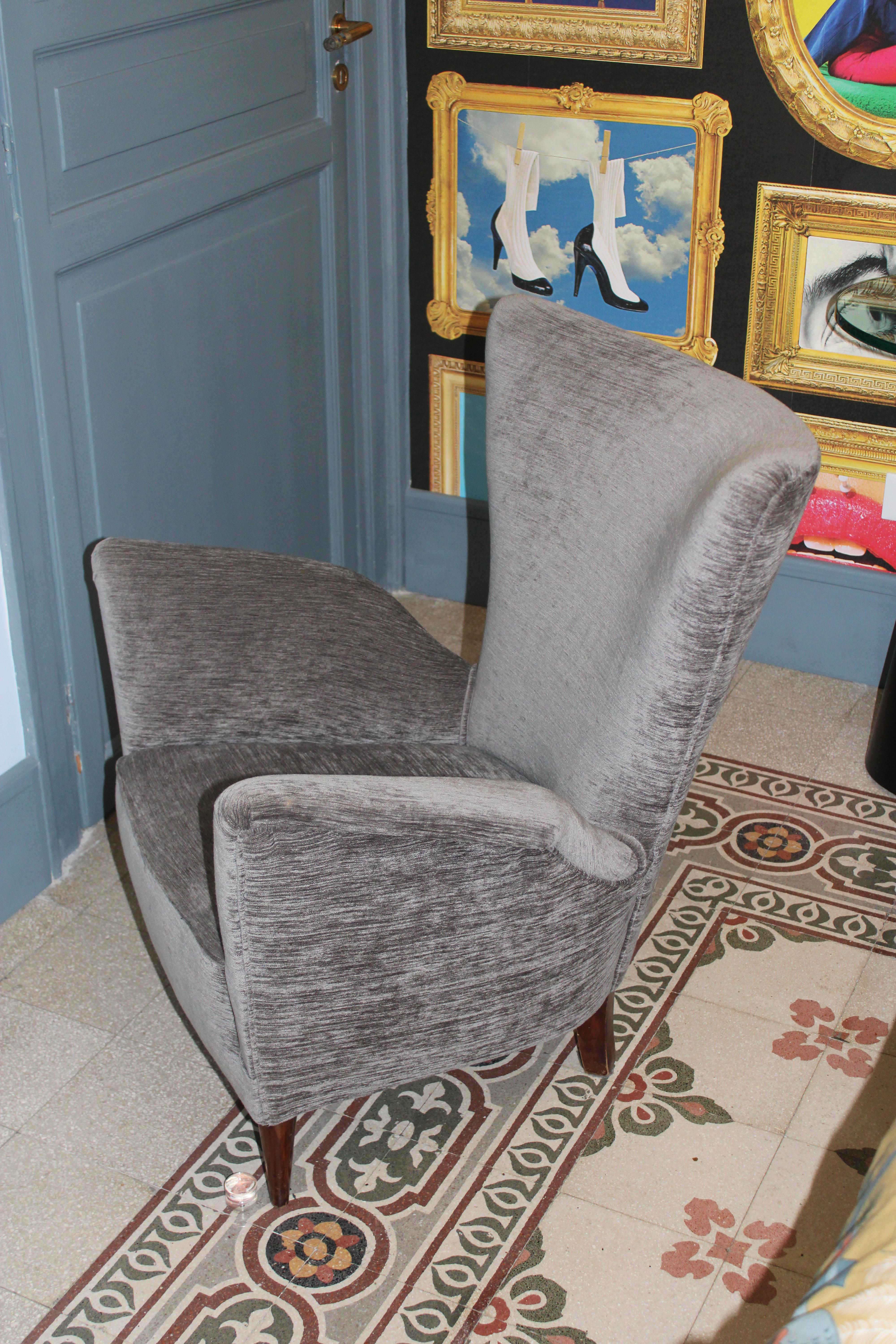 Fauteuil en velours gris foncé, pieds en bois.