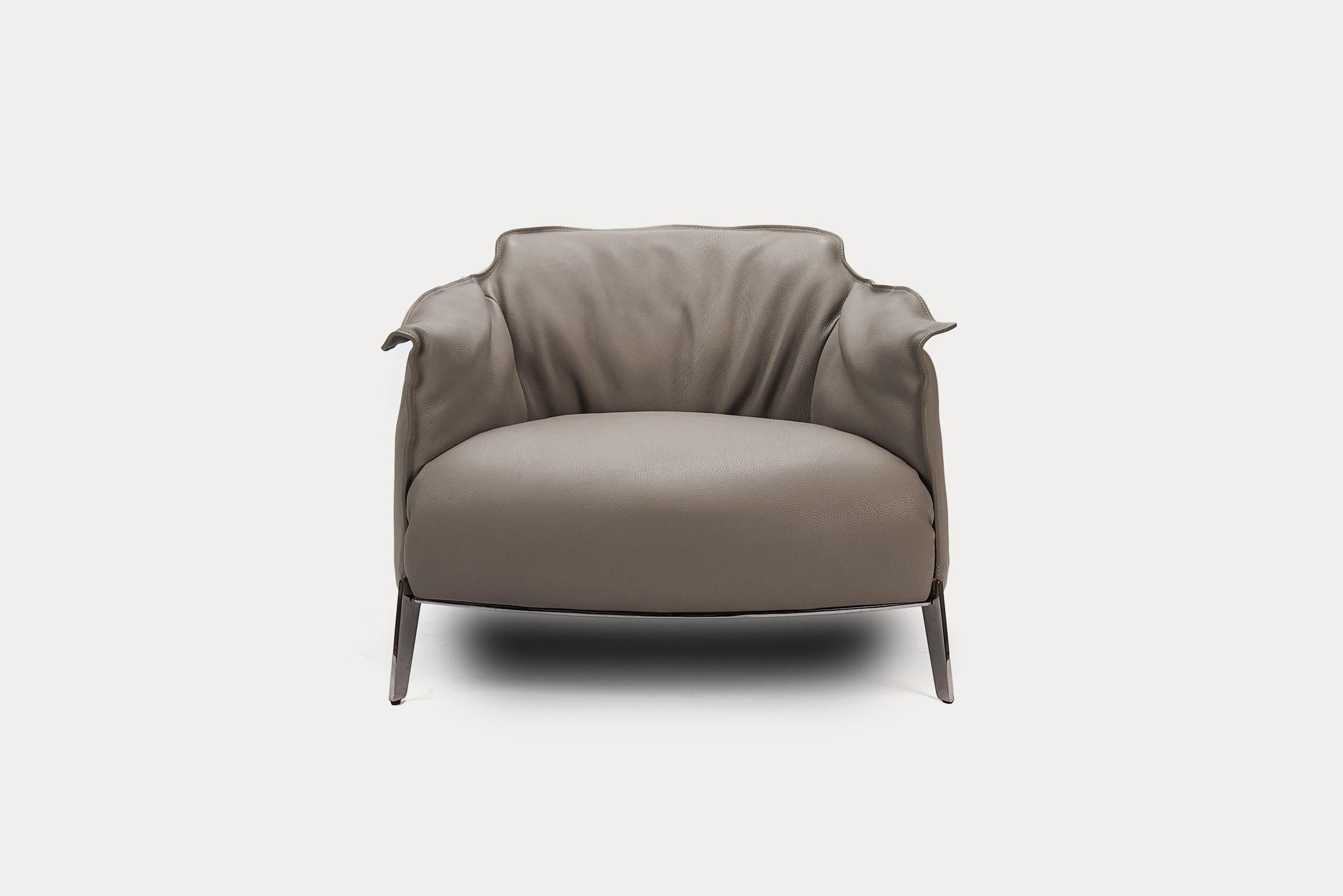 This set consists of one chair and the ottoman. Gran Comfort is the most generous chair of the Archibald series. Both chair and ottoman are upholstered in warm grey Safari leather. The stitching details, contrast between smooth and gathered leather,