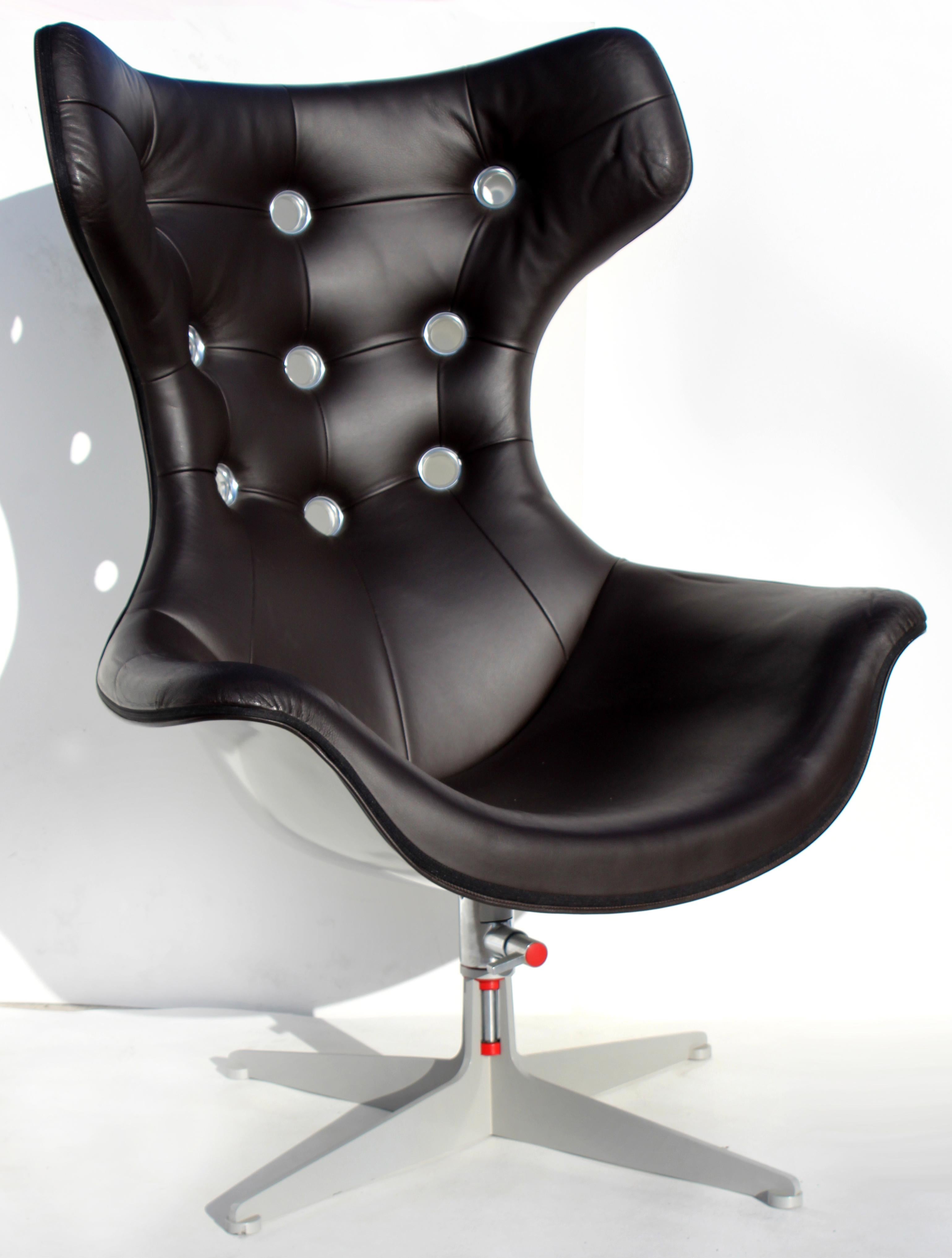 Offered for sale is a Poltrona Frau dark espresso leather Space Age wing-back swivel chair and ottoman with riveted openings to the back and an adjustable steel base. This wonderfully designed and adjustable chair and ottoman have the finest quality