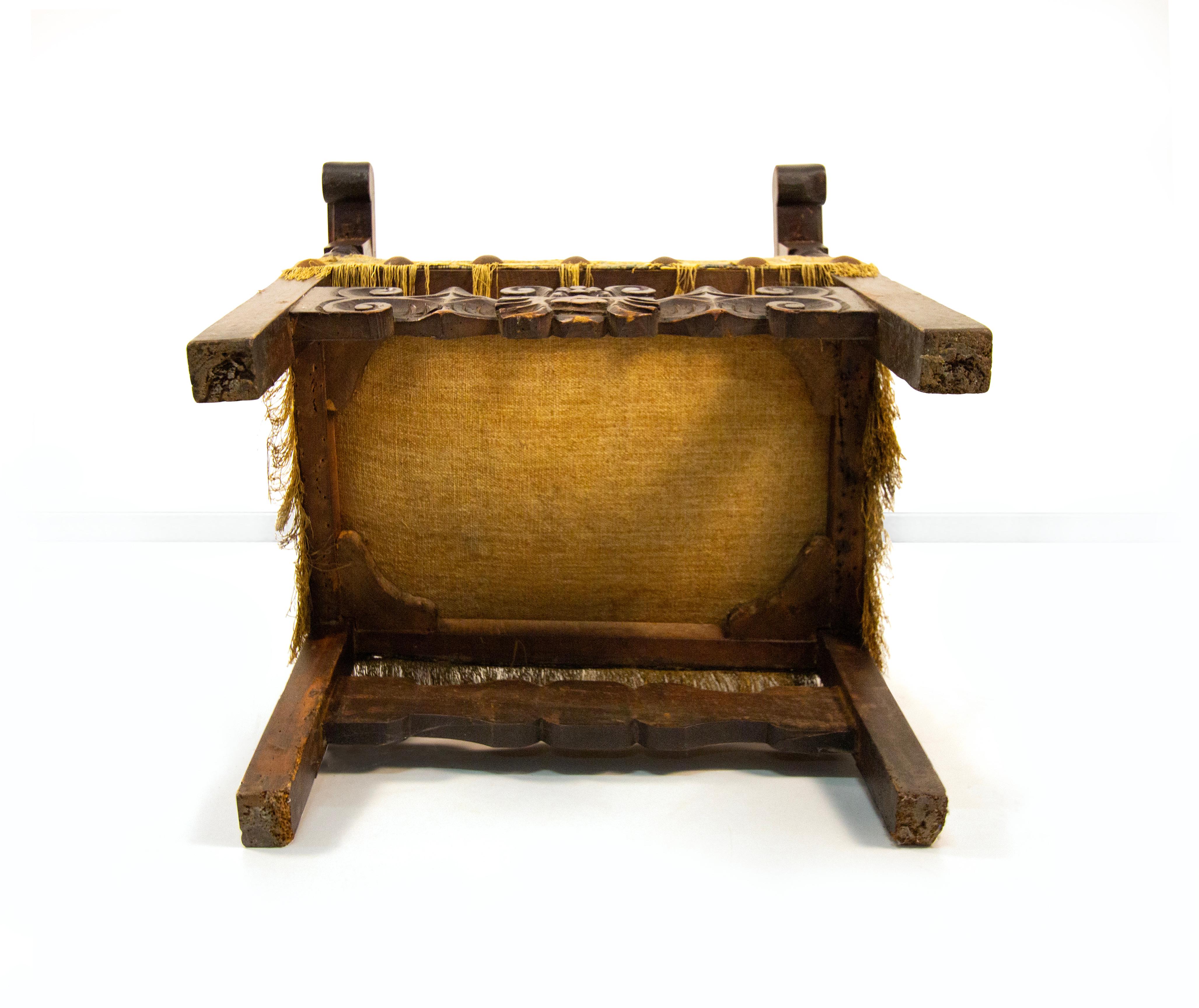 Poltrona in noce, XVII secolo, braccioli lievemente sagomati su montanti torniti a fuso; gambe quadrangolari raccordate da una fascia scolpita e intagliata a volute. Schienenelemente und Sitzflächen aus geflochtenem und genietetem Messing, cm