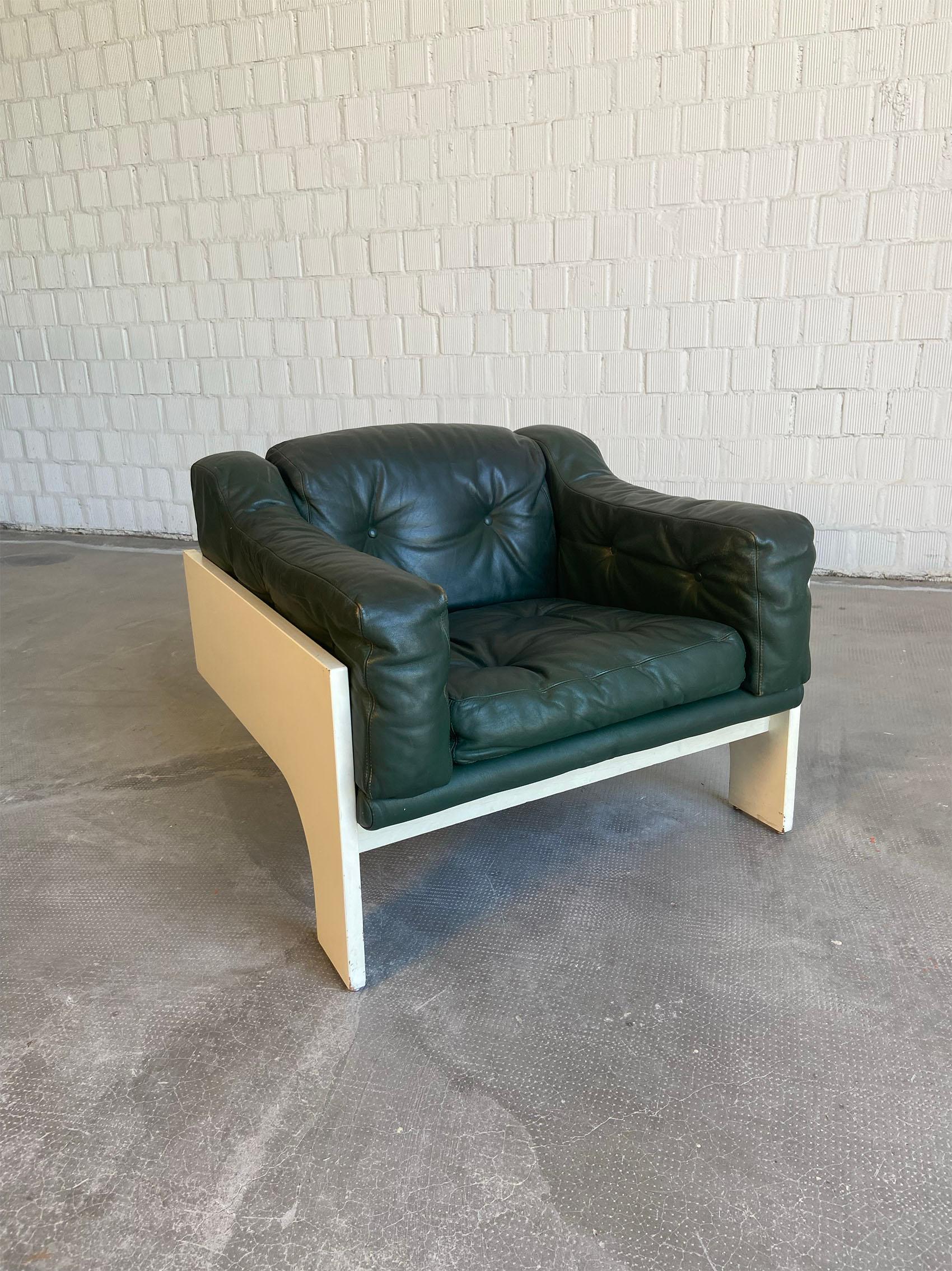 Armchair designed in 1960 for Sormani by Claudio Salocchi. The white lacquered wood frame is composed of rigid, geometric lines, contrasting with the comfortable, soft dark green leather seat. The chair is in good condition with some signs due to