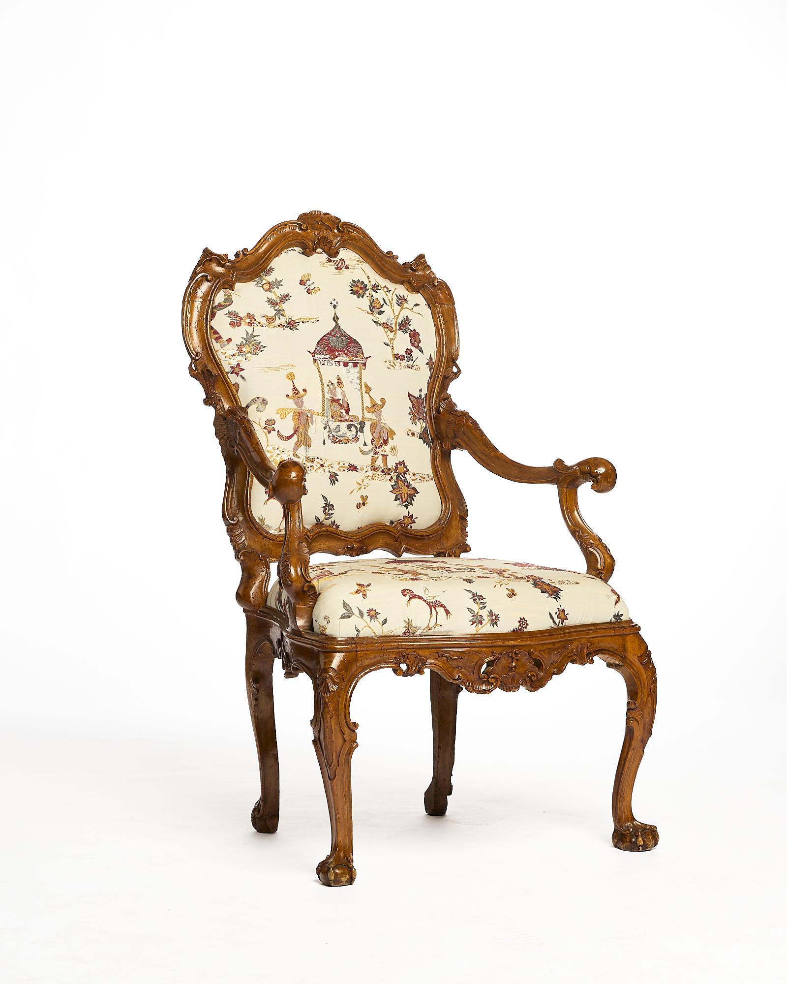 Questa poltrona veneziana del Settecento risale al pieno periodo rococò, con struttura in legno intagliato riccamente decorata da motivi floreali e gambe a zampa di leone. La tappezzeria con 