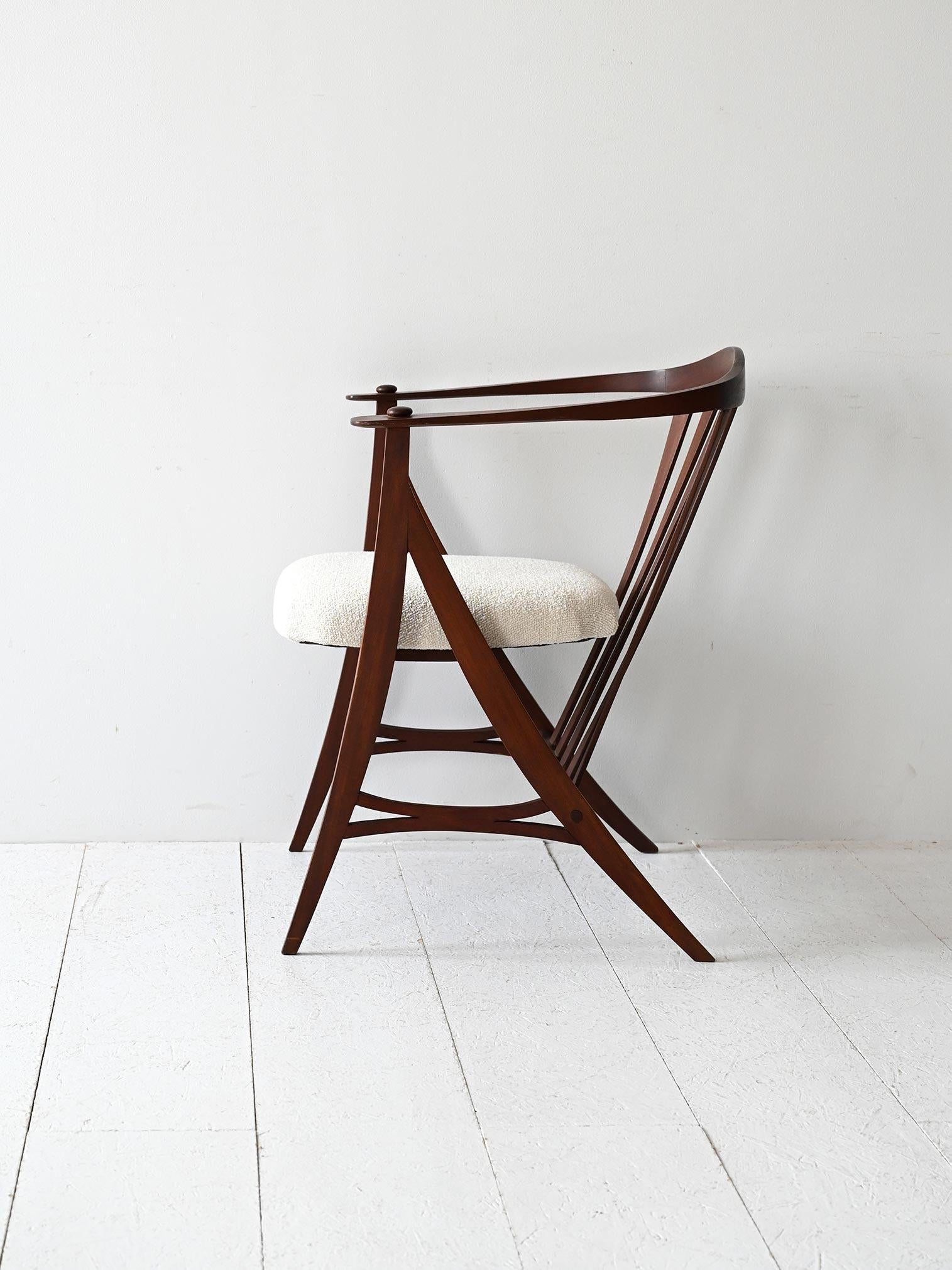 Vintage 1950s carved dark wood chair with thin arms and new light bouclé upholstery.

Sculptural vintage 1950s armchair with solid machined wood frame. The tapered armrests join the backrest in a single continuous curved line, while the slender legs