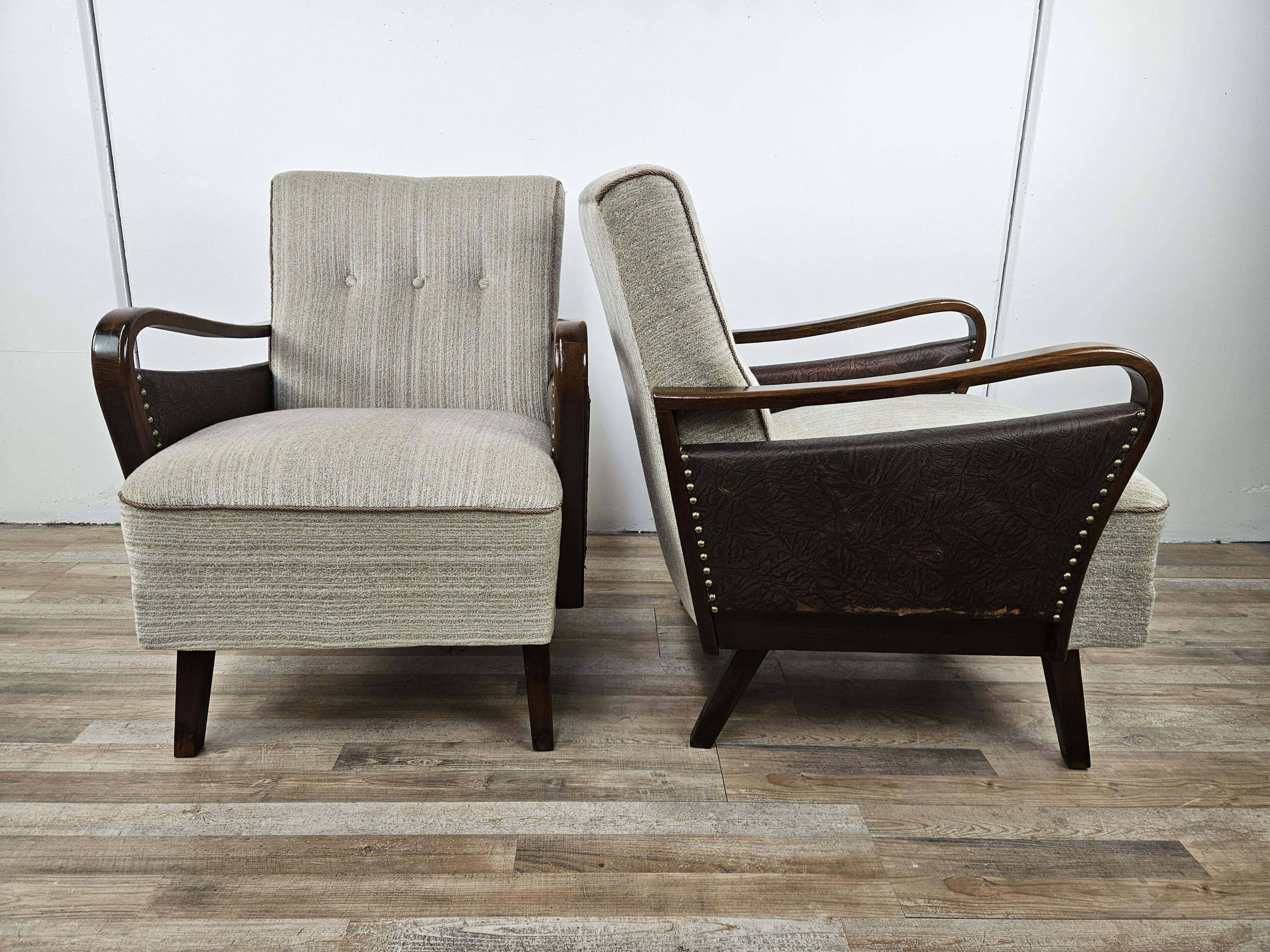 Poltrone Art Decò anni '40 con struttura in noce e rivestimento in tessuto e pelle, decorate da borchie ai lati.

Da notare la struttura molto particolare come rende questa coppia di poltrone Art Decò eleganti e dal design moderno e