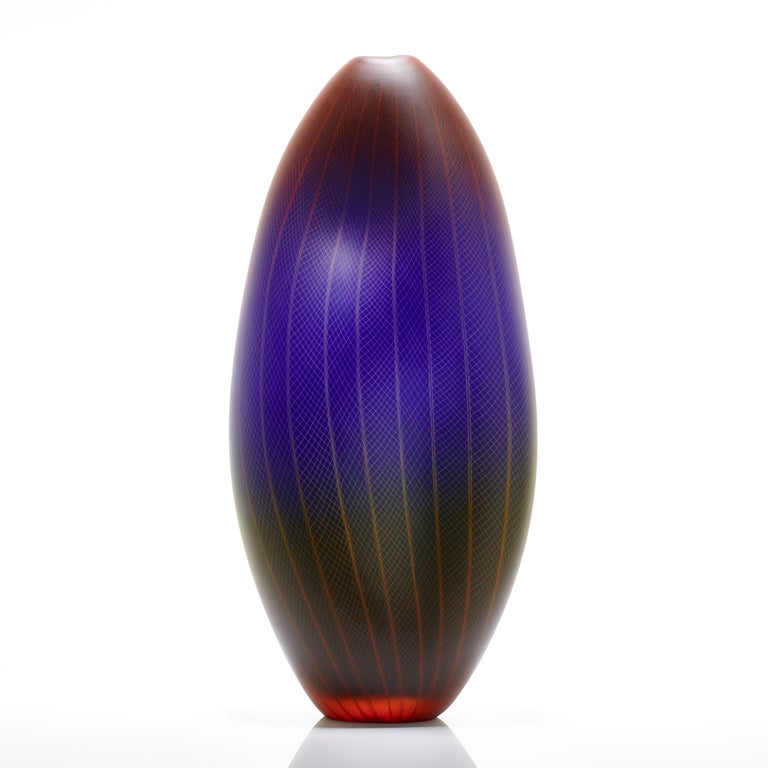 Polychromatic Interleave 006, is a unique handblown glass vessel with fine filigree white cane detail by the British artist Liam Reeves. The three colours of glass in red, blue and green, merge in the making to create a larger spectrum of hues where