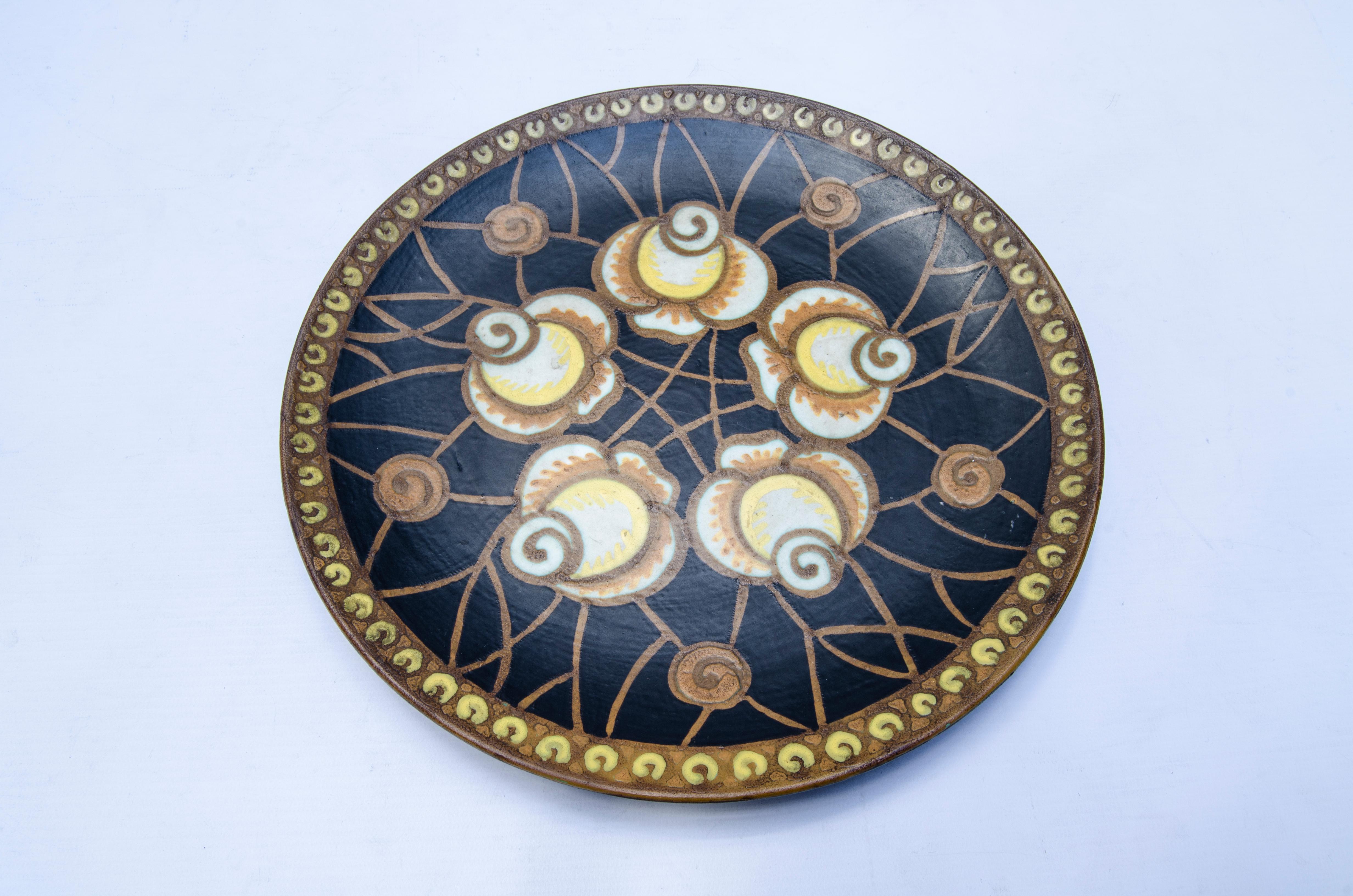 Polychrome ceramic plate with a design of stylized floral motifs in black, yellow, orange, brown and white. This plate is illustrated in: L'homme de Keramis, Charles Catteau de Dominique Corrieras, by Charles Catteau (1880-1966).

Signed CH Catteau,