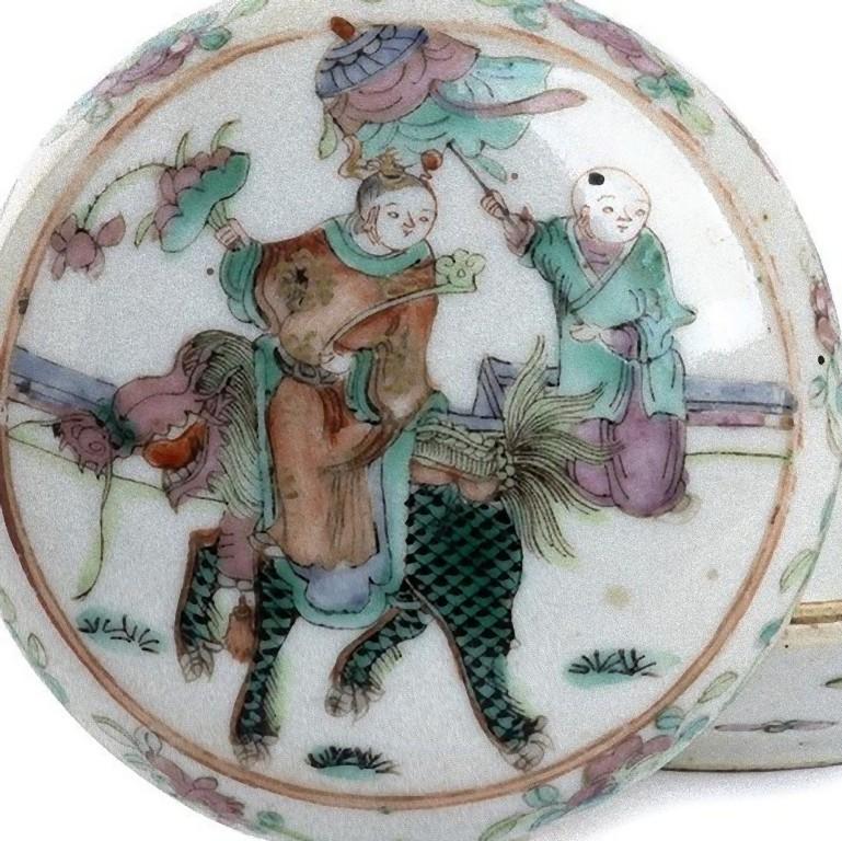 Cette boîte et son couvercle en porcelaine polychrome est un superbe objet décoratif, réalisé en Chine au début du 20e siècle.

Le couvercle bombé est décoré d'une scène représentant un garçon sur un animal mythologique, dans son dos un autre