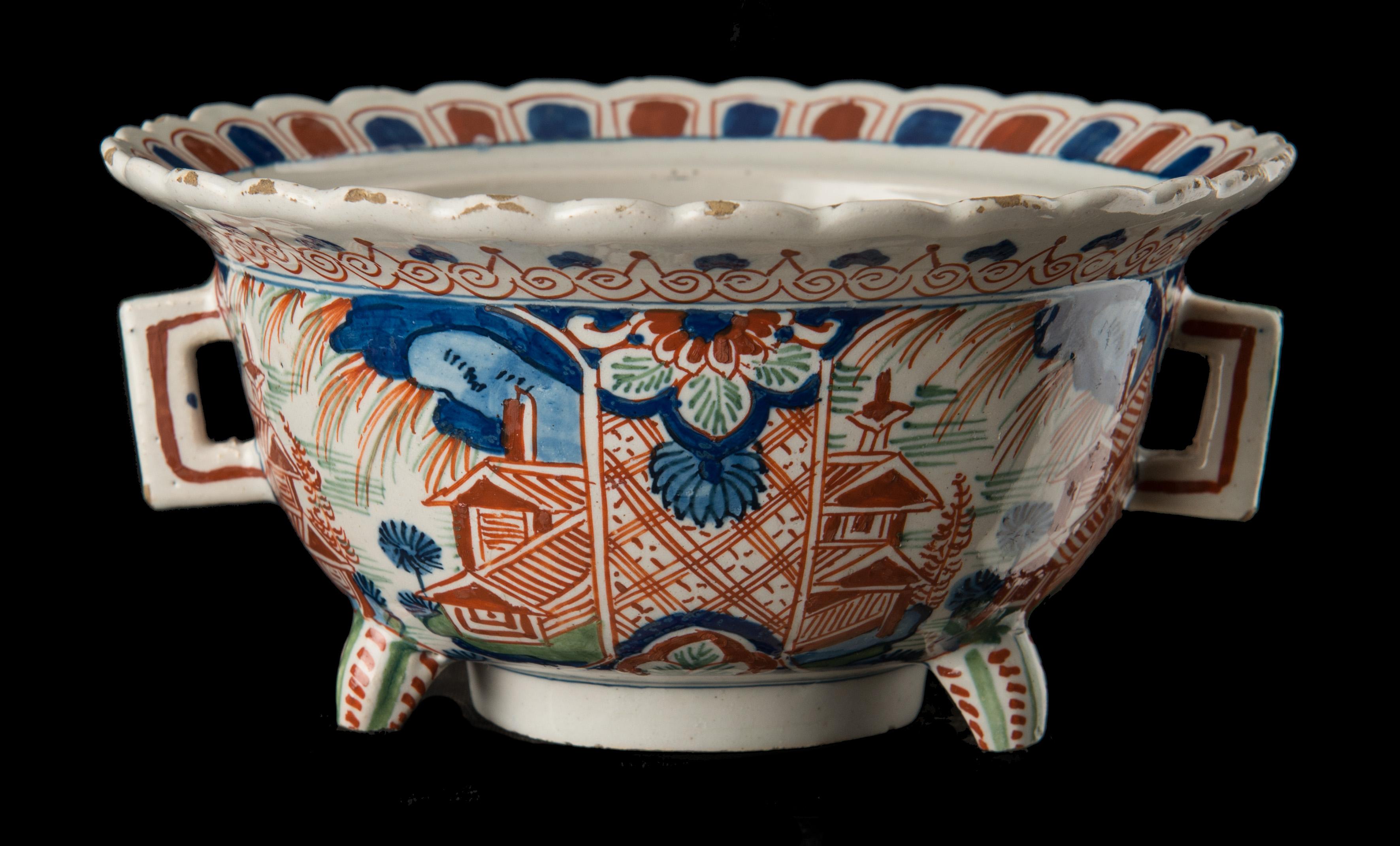 Polychrome chinoiserie bowl. Delft, 1710-1730 

This polychrome bowl stands on a high foot and has three extra feet. The two angular handles are vertical, the spreading upper rim is profiled. The bowl is painted with four chinoiserie landscapes,