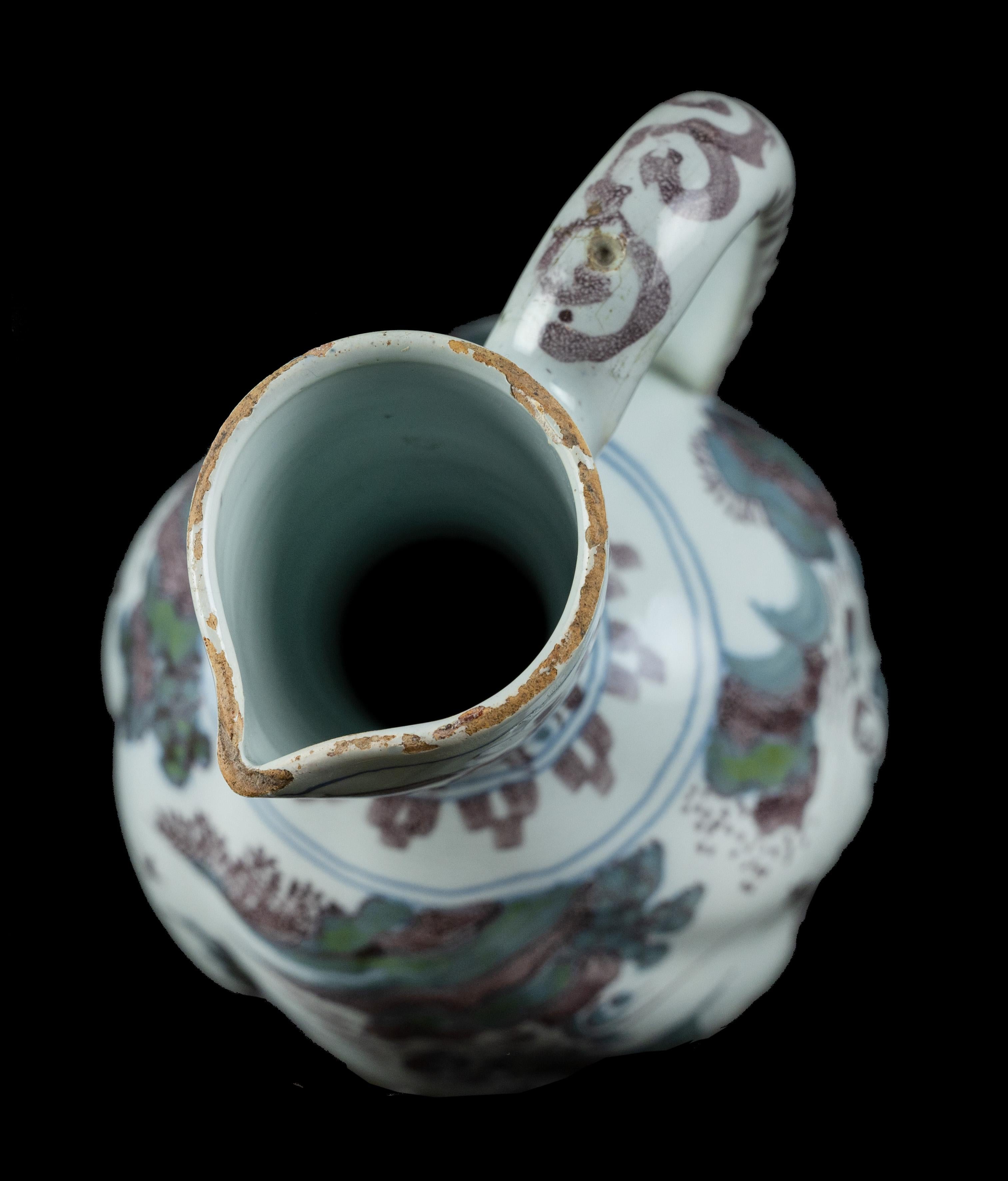 Polychrome chinoiserie wine jug. Delft, circa 1680
The polychrome wine jug has an ovoid and turned body on a low spreading foot, a conical neck with spout and a handle with a scroll finish. The jug is painted in blue, purple and green with a