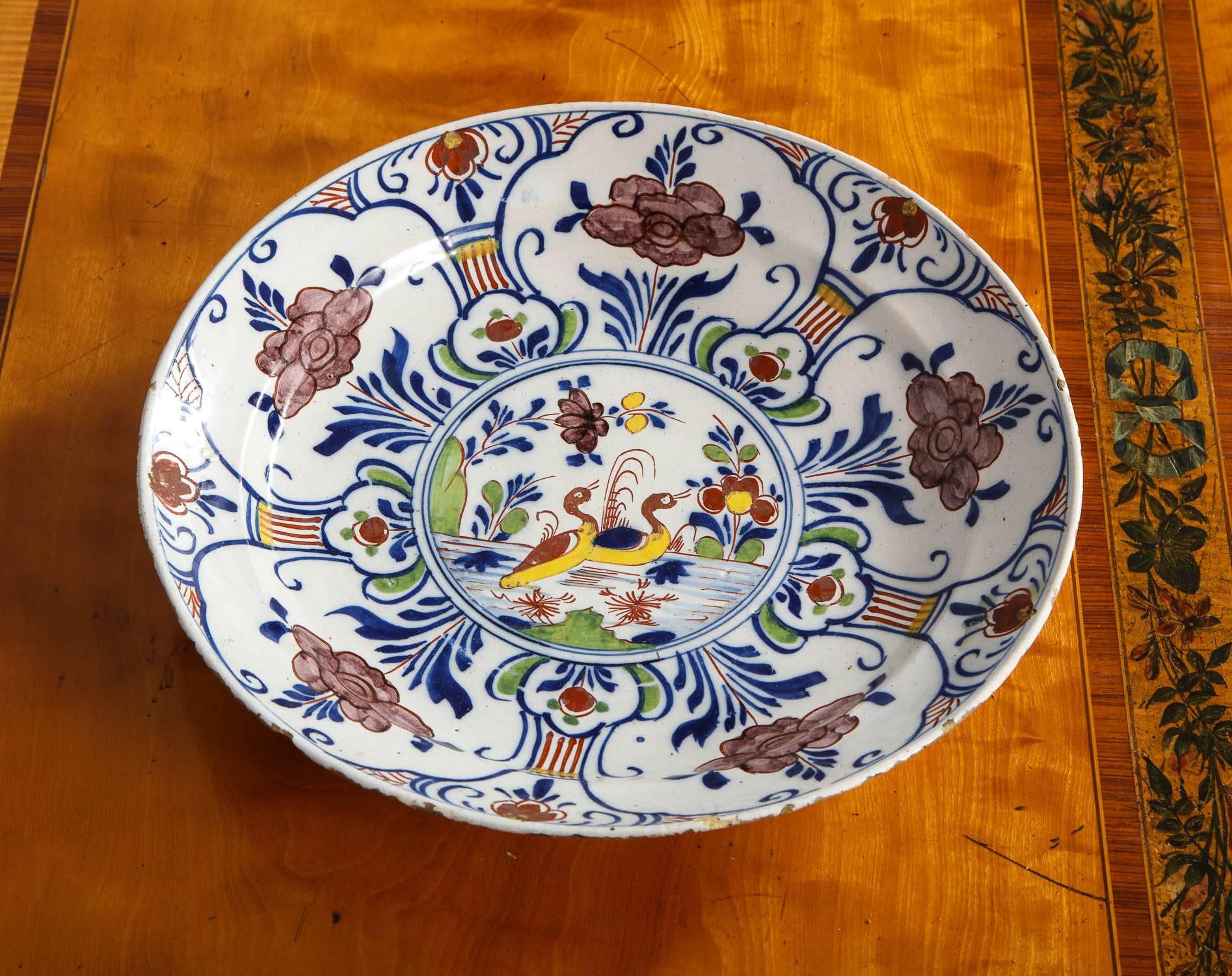 Fine 18th century Dutch delft charger/deep dish featuring two ducks in a pond with foliate decorated border, in manganese, yellow, blue and green glazes, having pottery mark 