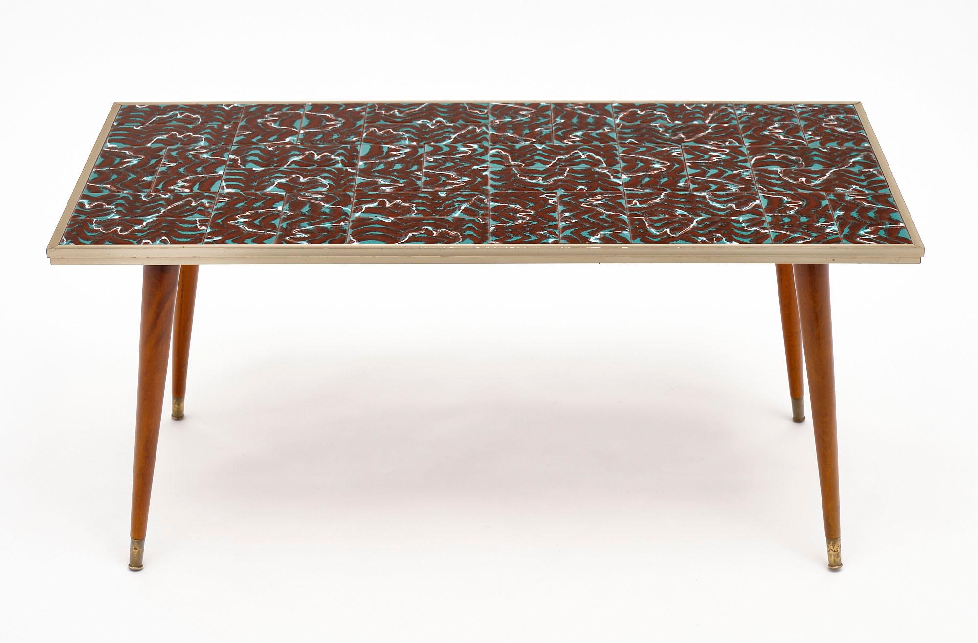 Polychrome French tiled coffee table from Vallauris. The tile work is framed in metal trim and supported by four tapered legs. The wooden legs are finished with a lustrous French polish.