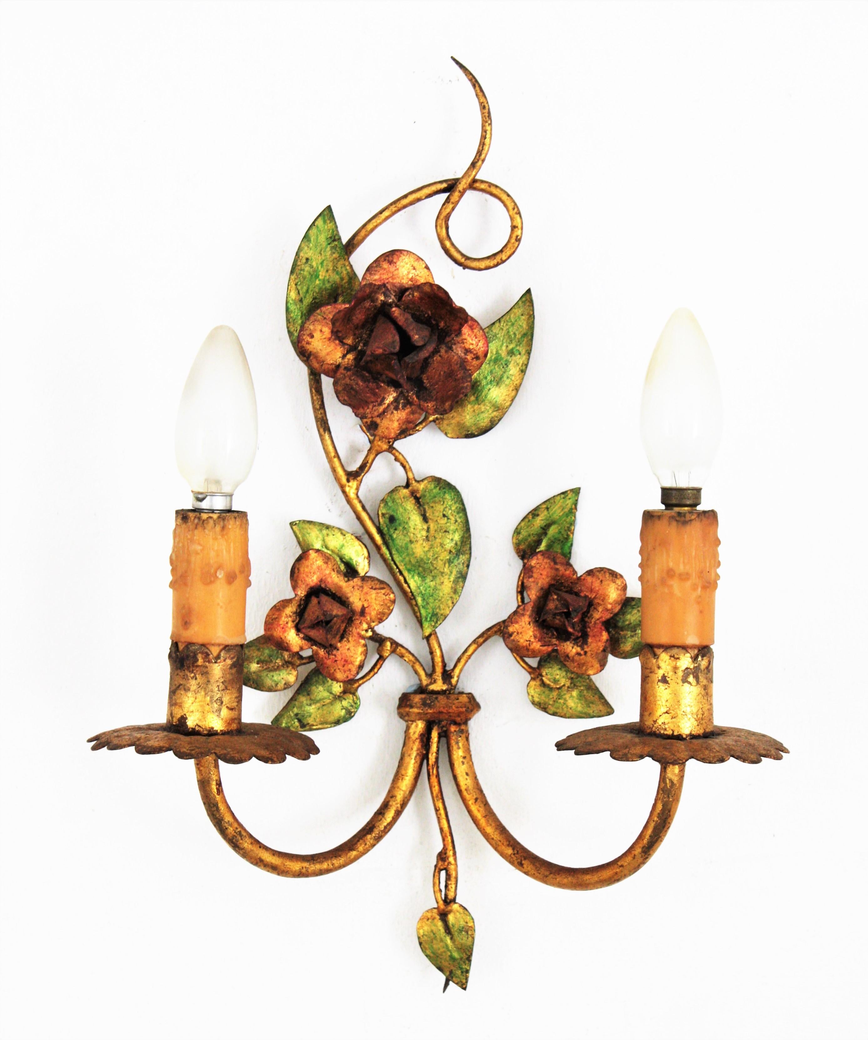 Elegant gilt wrought polychromed iron floral two-light wall sconce with paper shades, France, 1940s.
This wall sconce has two arms decorated by polychrome gold leaf gilt iron roses and leaves.
Each arm has a wax candlelabra holder for an E14