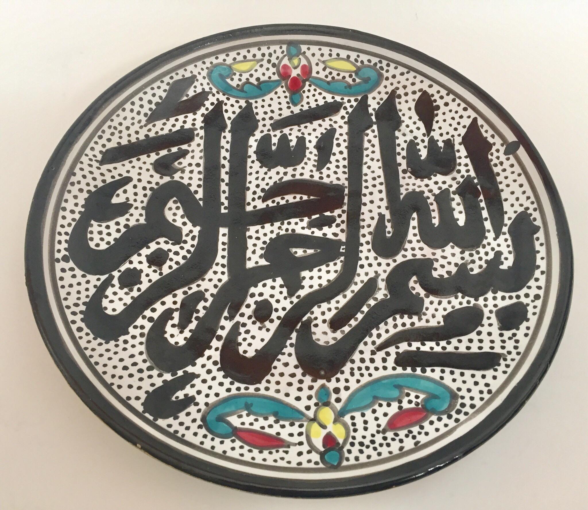 Polychrome hand painted and handcrafted Moorish ceramic wall decorative plate with polychrome Ottoman floral design and Islamic Koranic Calligraphy writing in the center.
