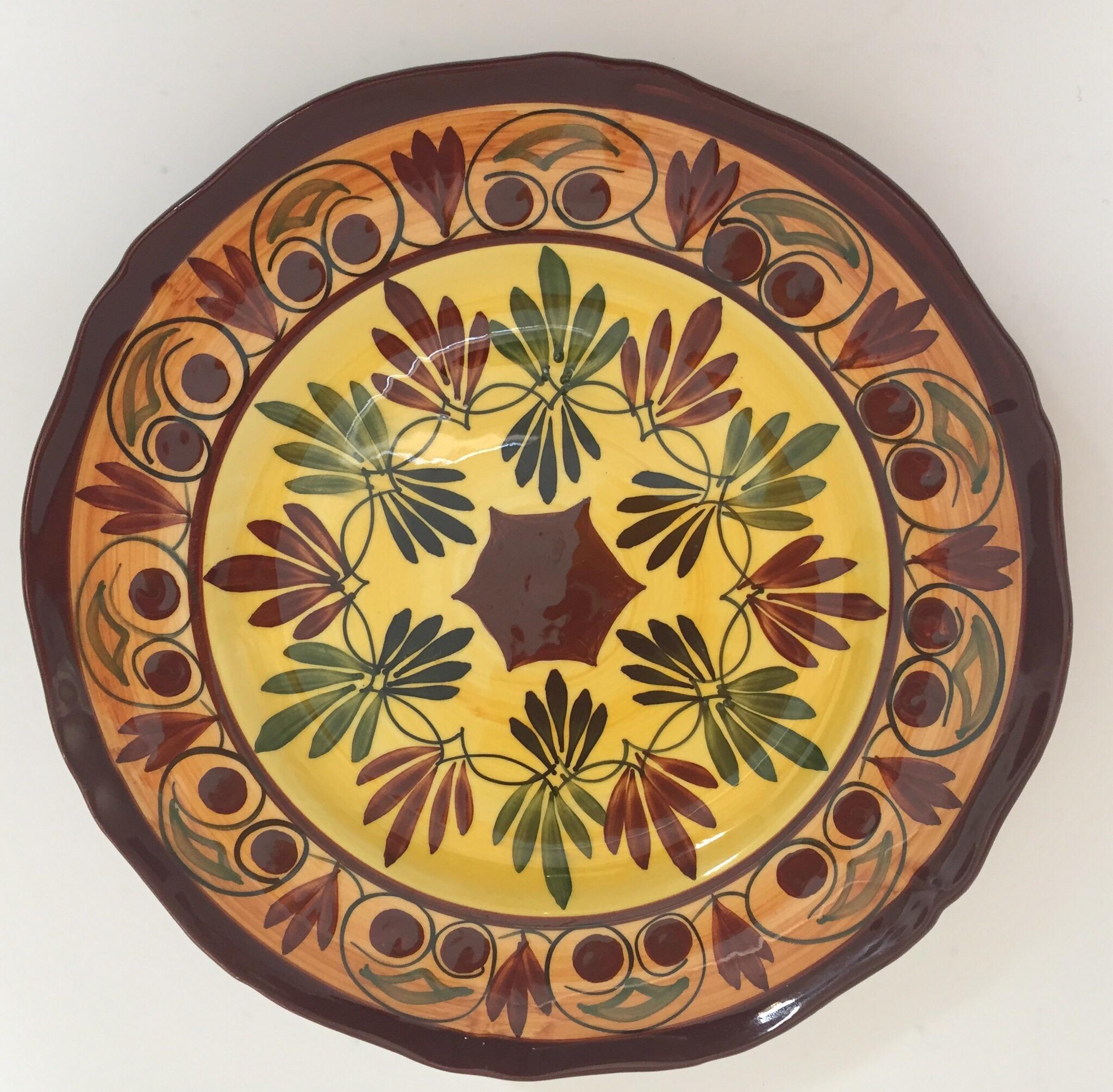 Polychrome hand painted and handcrafted ceramic wall decorative plate with polychrome floral design. 
It has a beautifully hand painted flowers in burgundy, yellow and green foliage. 
The back of the plate is signed. 
