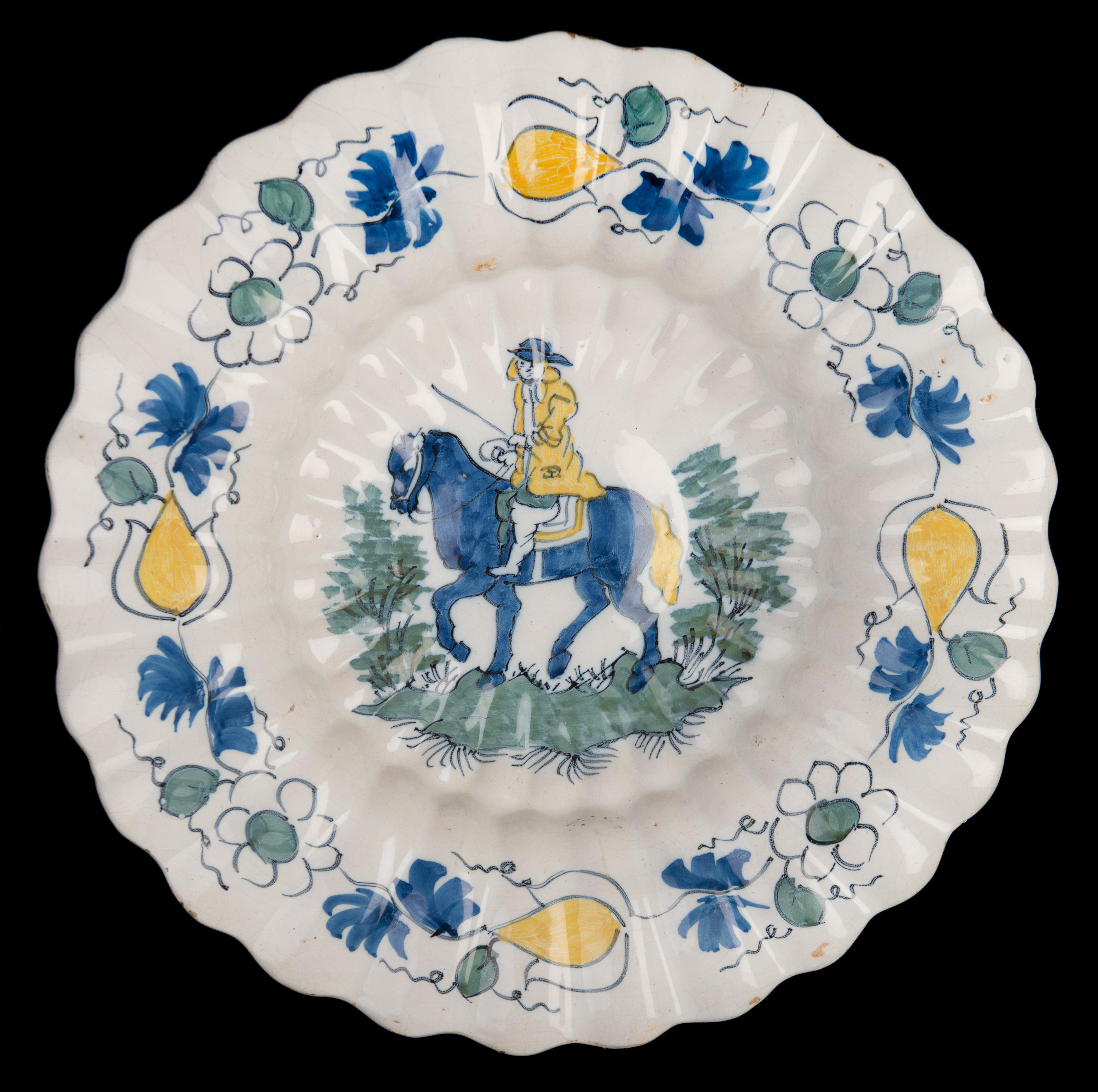 Polychrome lobed dish with horseman. Delft, 1690-1700.
Dimensions: diameter 33,8 cm / 13 in.

The lobed dish is composed of twenty-seven double lobes and is painted in polychrome with a central motif of a horseman. The border is decorated with a