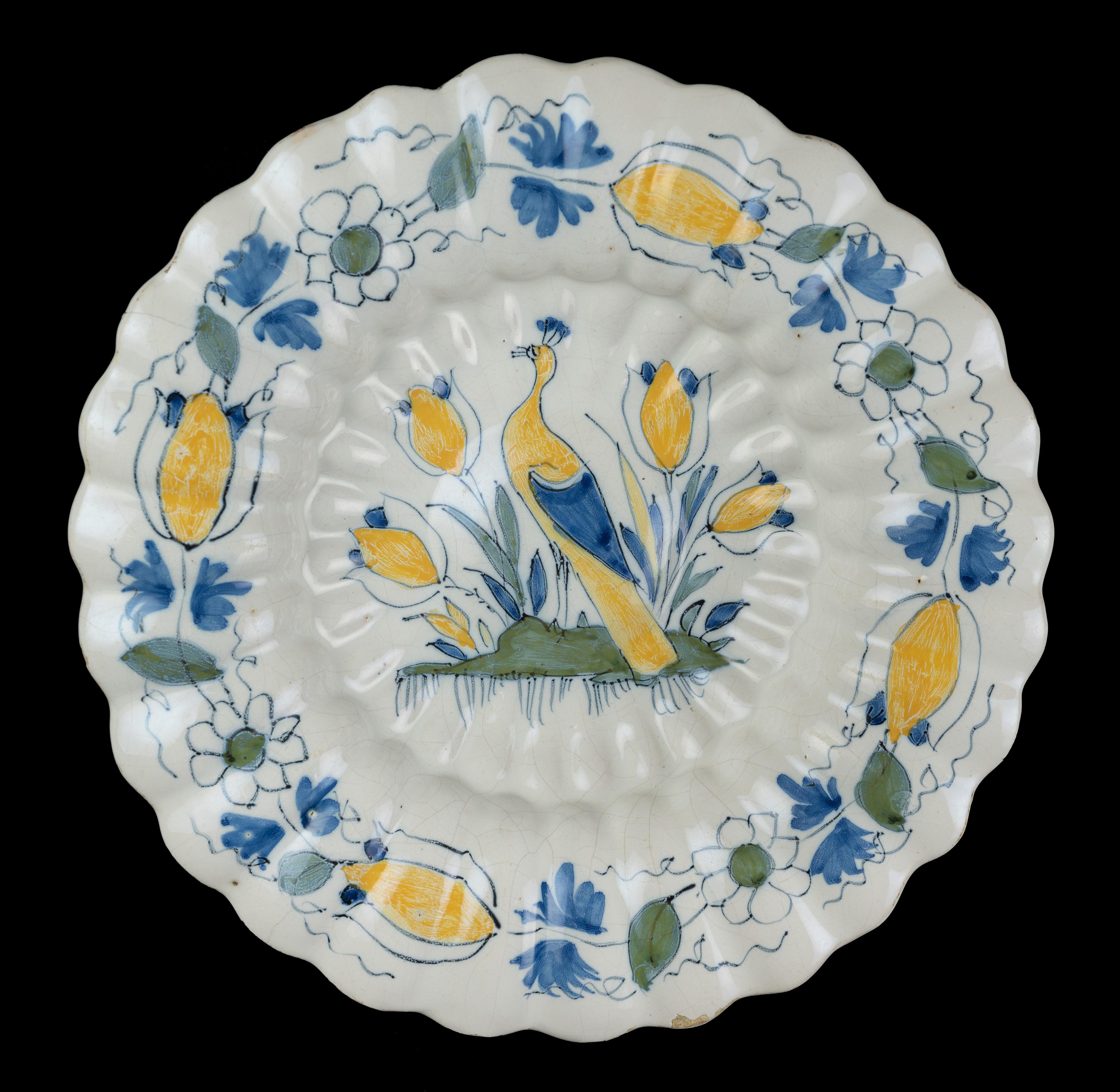 Polychrome lobed dish with peacock and tulips. Delft, circa 1690.
Dimensions: diameter 33,5 cm / 13.18 in.

The polychrome lobed dish is composed of twenty-seven double lobes and is painted in the centre with a peacock between four tulips on a