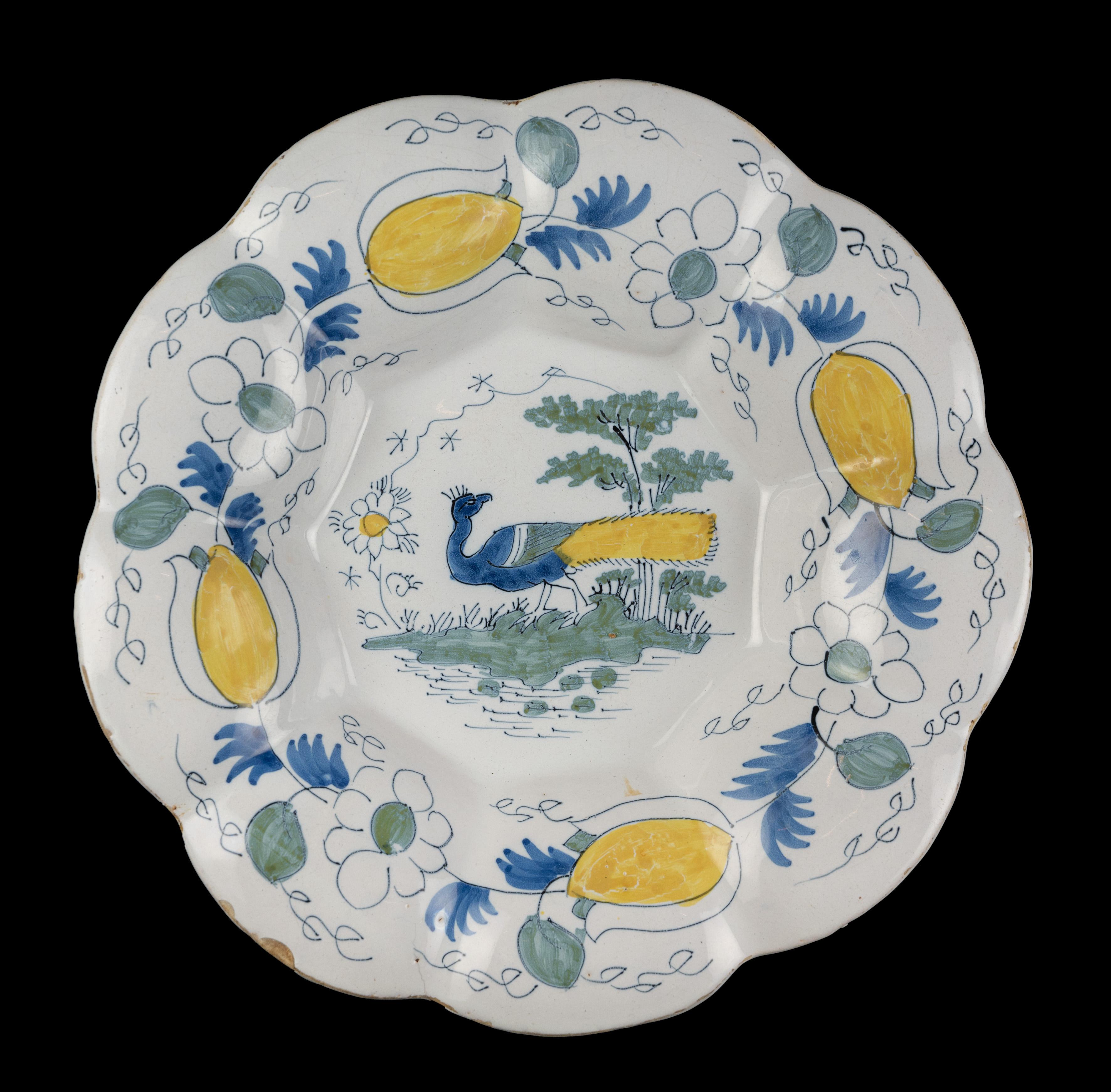 Polychrome lobed dish with peacock in landscape. Delft, circa 1690.
Dimensions: diameter 34,9 cm / 13.74 in. 

The polychrome lobed dish is composed of nine wide lobes and is painted in the centre with a peacock in a water landscape with plans