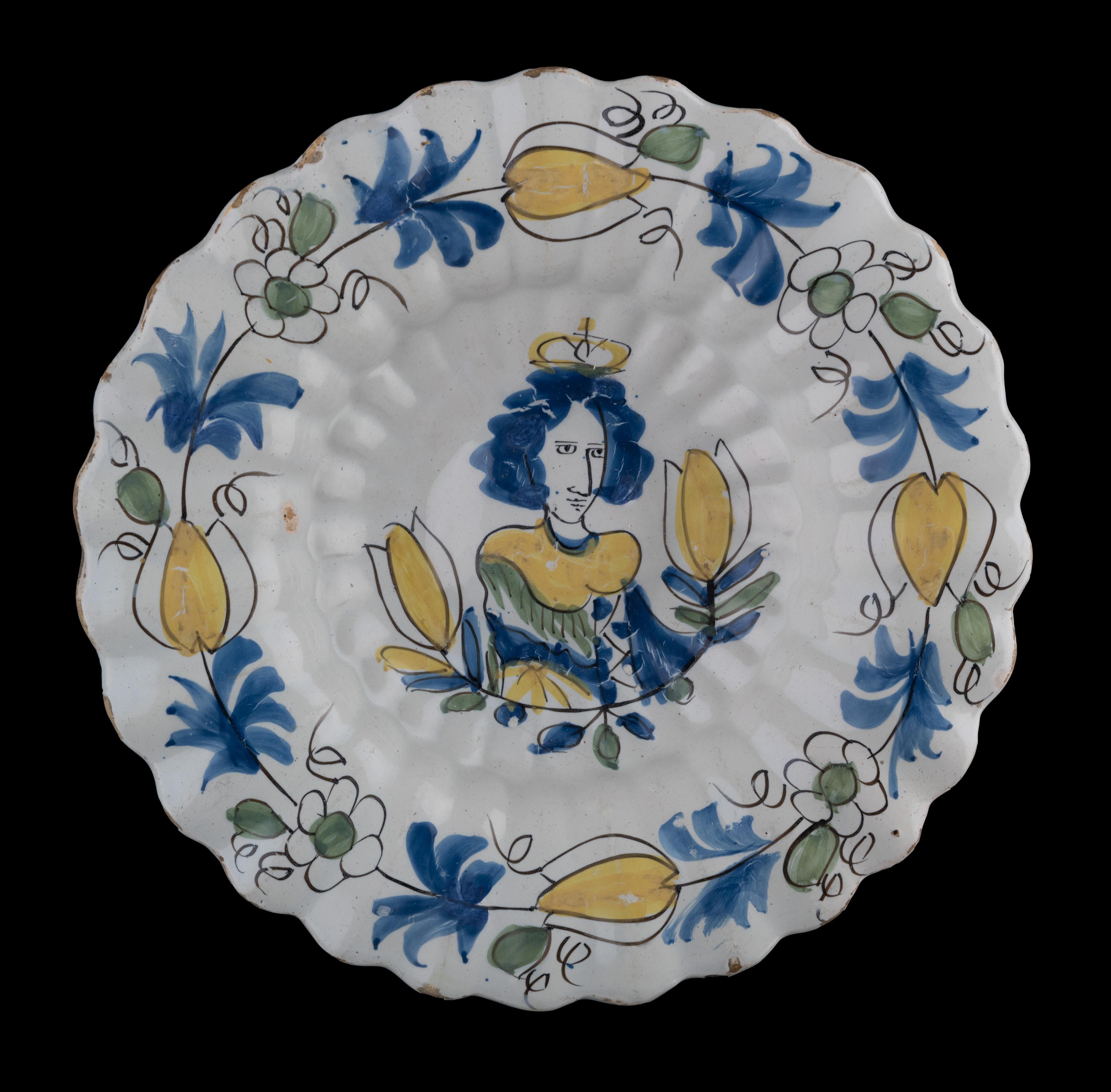 Polychrome lobed dish with Queen Mary II Stuart
Delft, circa 1690 

The polychrome lobed dish is composed of twenty-seven double lobes and painted in blue, green and yellow with a depiction of Queen Mary II Stuart between two tulips. The border is