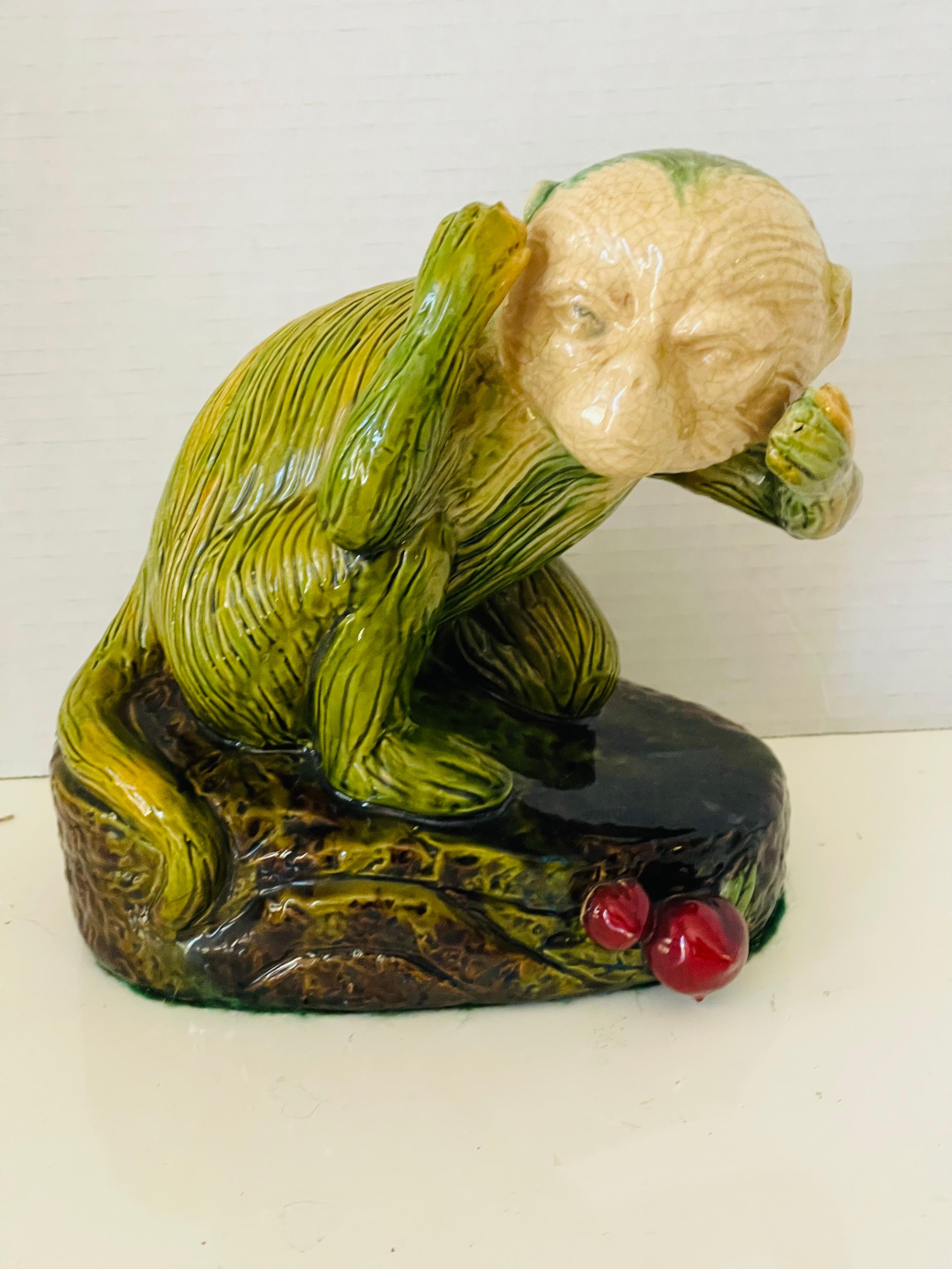 Figurine vintage en majolique polychrome représentant un singe assis avec des cerises. 10